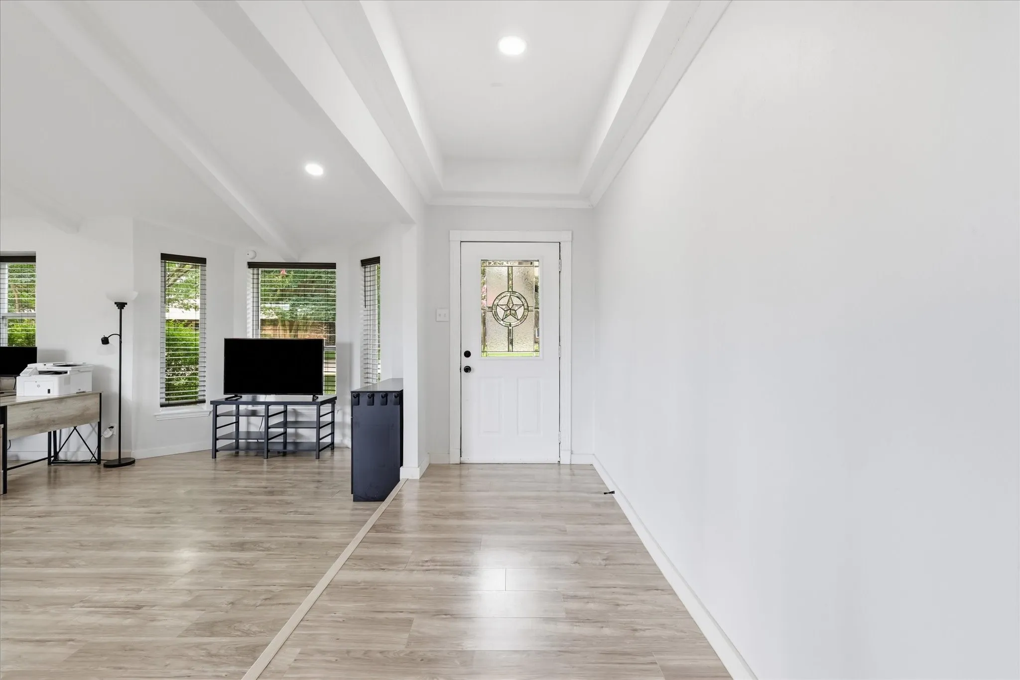 Entryway featuring a decorative frosted glass door, light wood-finish flooring, recessed lighting, and a tray ceiling