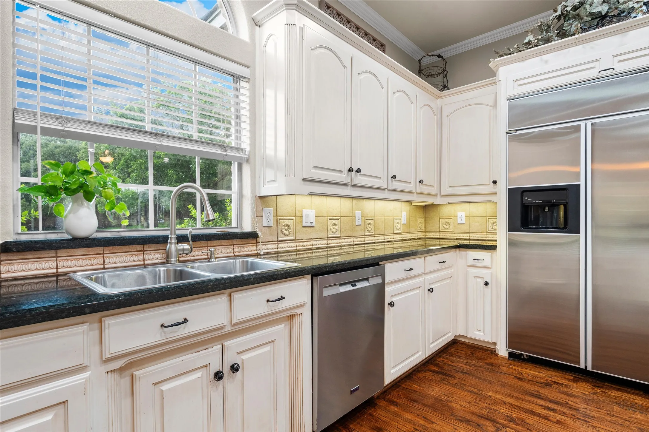 Kitchen featuring white cabinetry, granite countertops, a double basin stainless steel sink, and stainless steel appliances including a built-in refrigerator and dishwasher