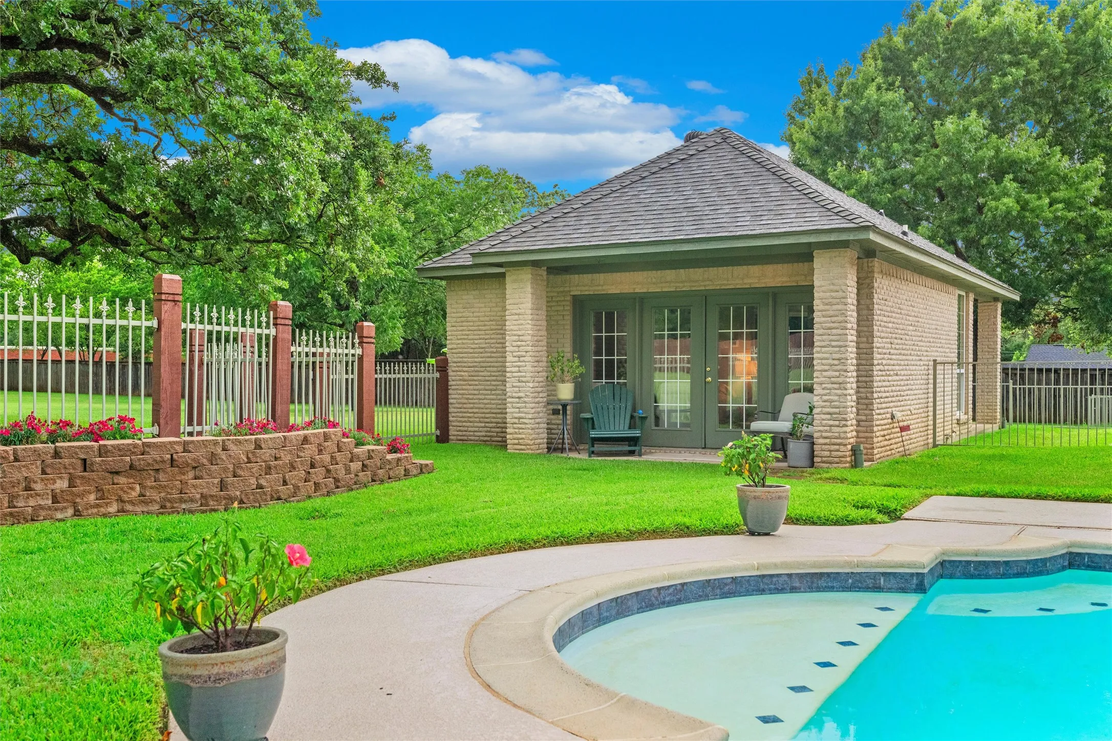 Detached brick guest house with a gabled roof and covered patio