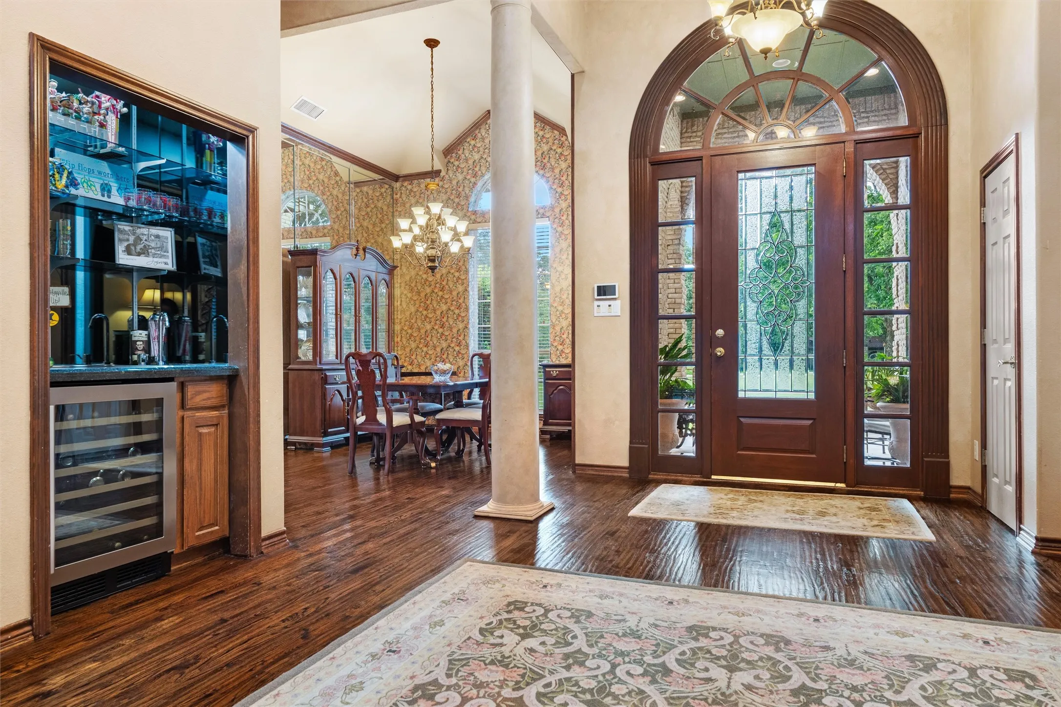 Grand entry featuring an arched wood-paneled door with leaded glass, flanked by sidelights and a transom