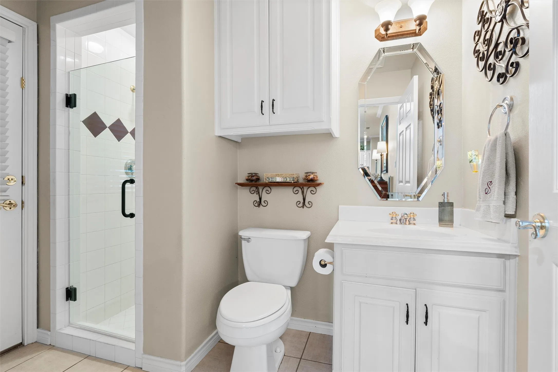 Dedicated full bathroom with access to the pool area and split 4th bedroom. Glass-enclosed shower featuring white subway tile with accent diamonds.