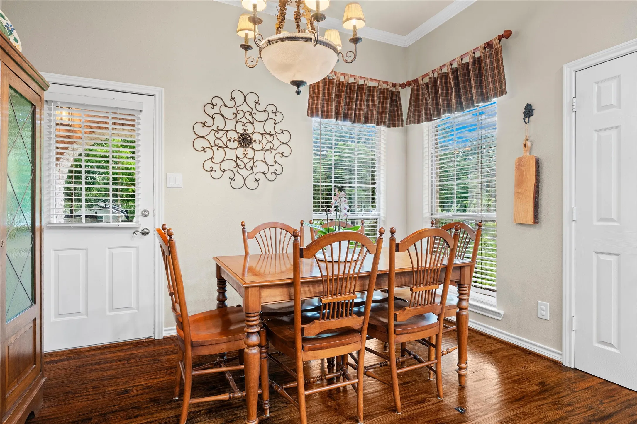 Dining area featuring wood-finish flooring, a decorative chandelier, and abundant natural light from multiple windows with blinds