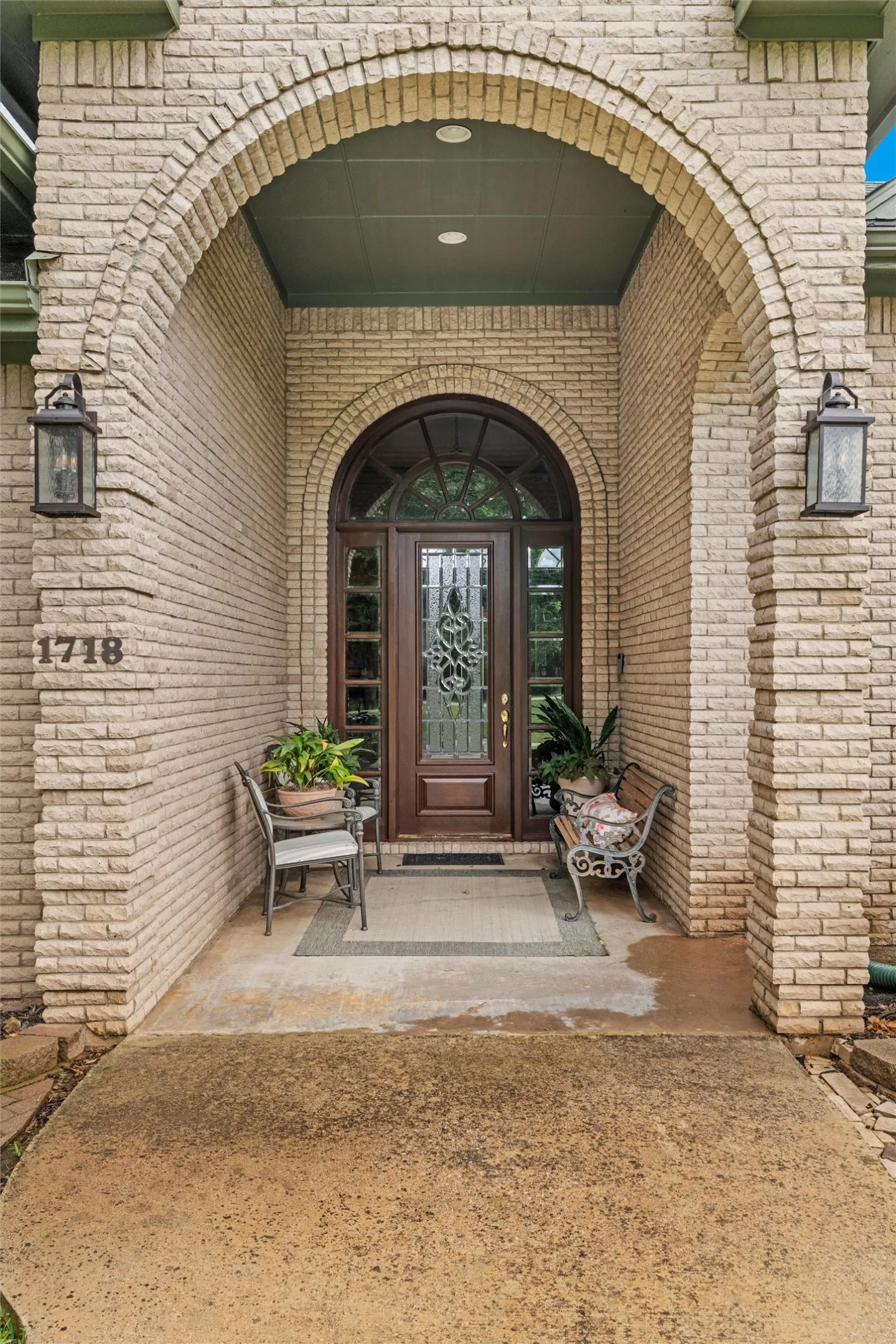 Arched brick entryway featuring a wood front door with an arched transom, decorative glass inserts, and sidelights