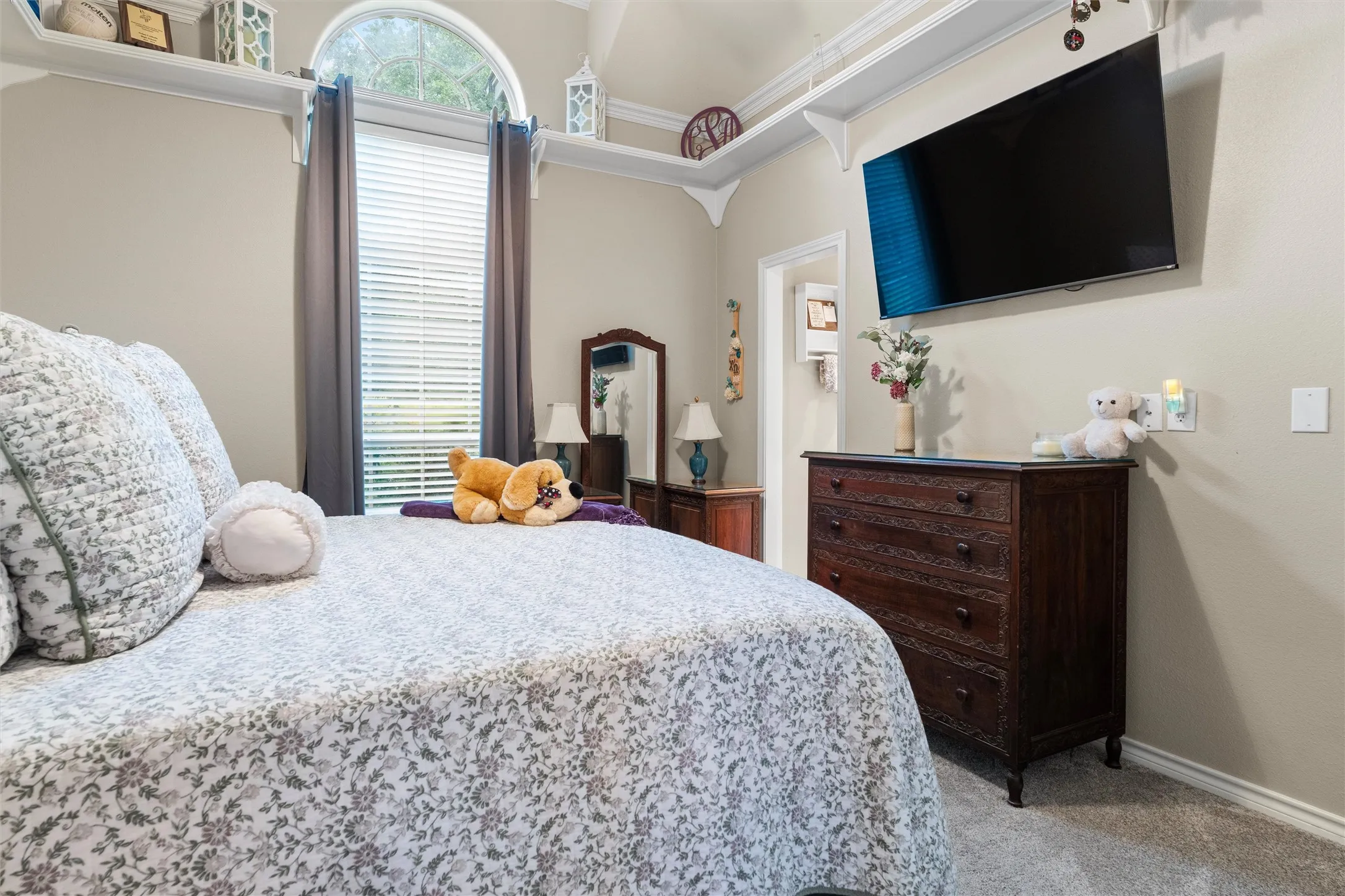 Bedroom with arched window, overhead shelving, neutral wall paint, and carpet flooring. Jack n Jill bathroom.