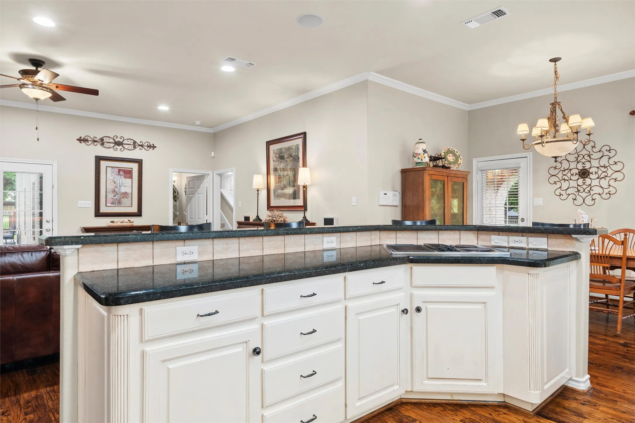 Kitchen island with white paneled cabinetry, granite countertops, and a tiled backsplash