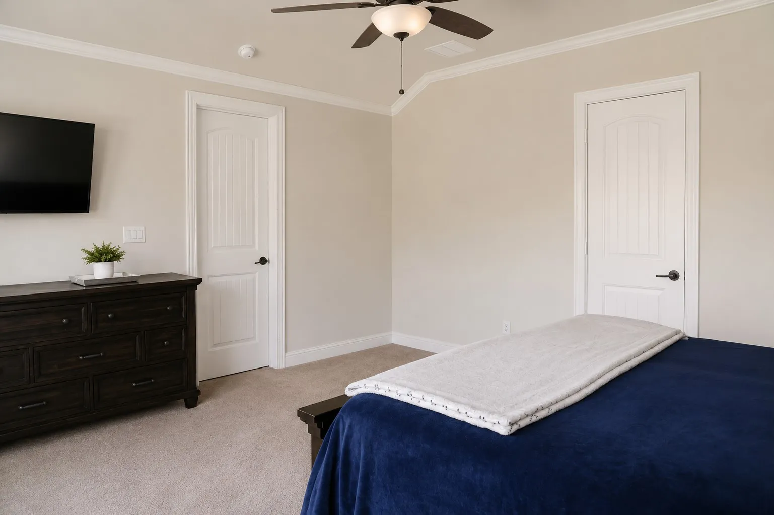 Neutral tone walls with crown molding, carpet flooring, and a ceiling fan with integrated lighting