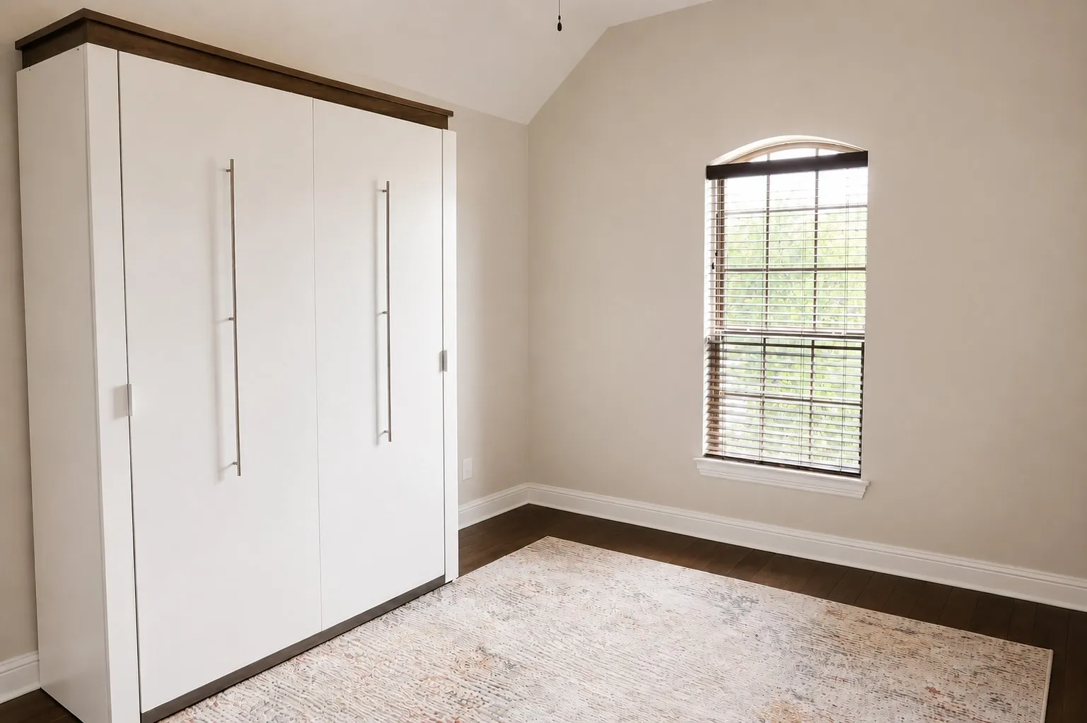 White built-in wardrobe with dark wood-finish trim, featuring long brushed-nickel pulls