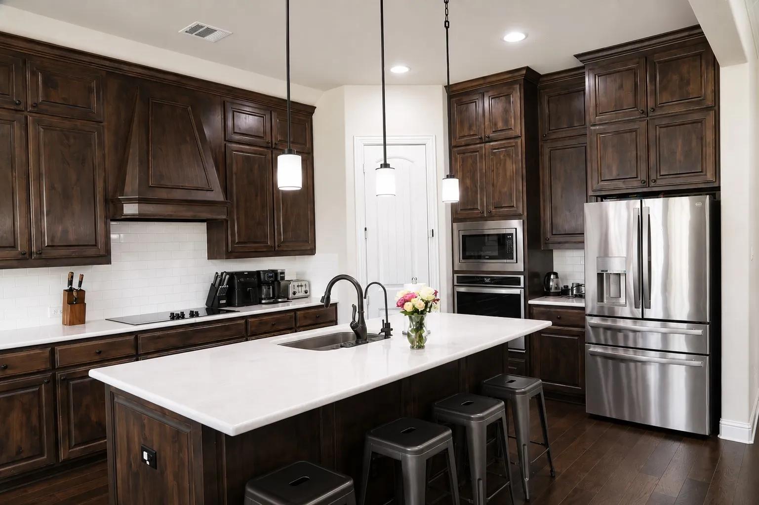 Kitchen featuring dark wood cabinetry, a white subway tile backsplash, and a large central island with a white countertop