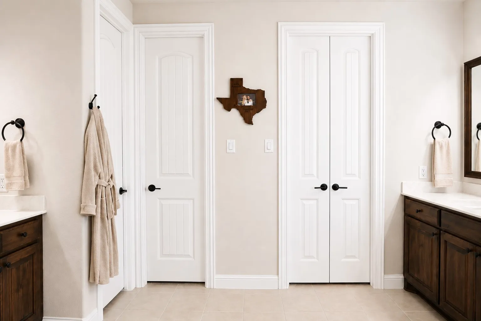 Bathroom featuring dual wood-finish vanities with light countertops, white paneled doors, and matte black hardware