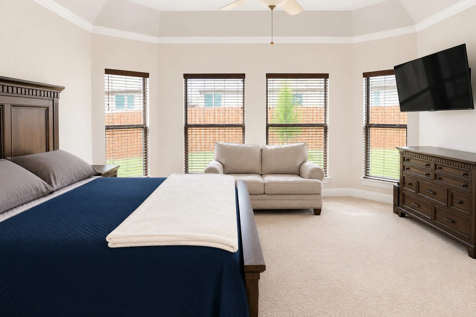Bay window with three large windows, crown molding, and a ceiling fan