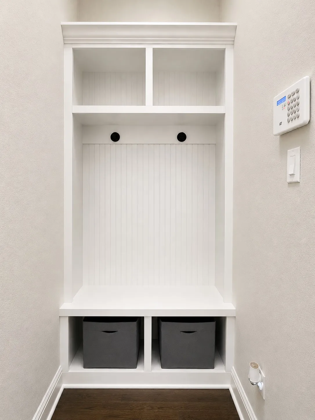 Built-in white storage unit featuring beadboard backing, crown molding, open shelving, and integrated cubbies