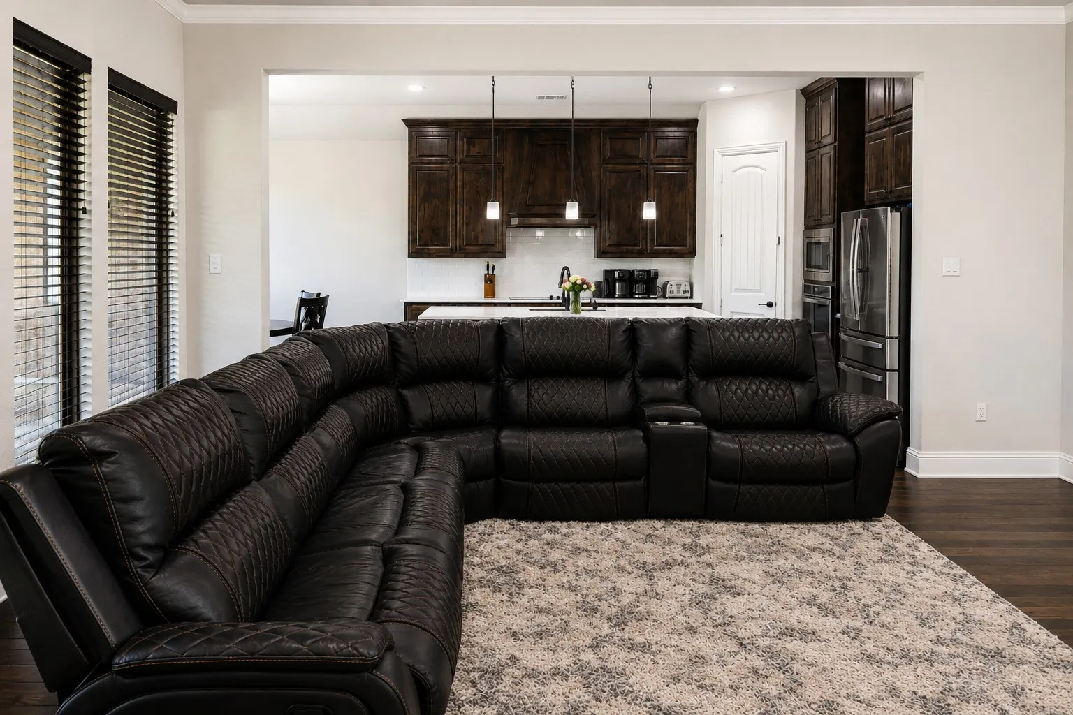 Open-concept living area featuring rich wood-finish flooring, crown molding, and recessed lighting
