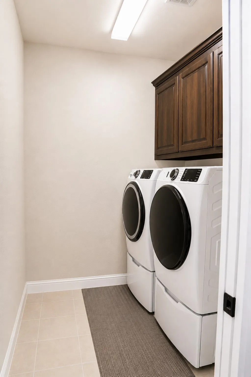 Laundry area featuring tile flooring, white baseboards, and a built-in dark wood cabinet
