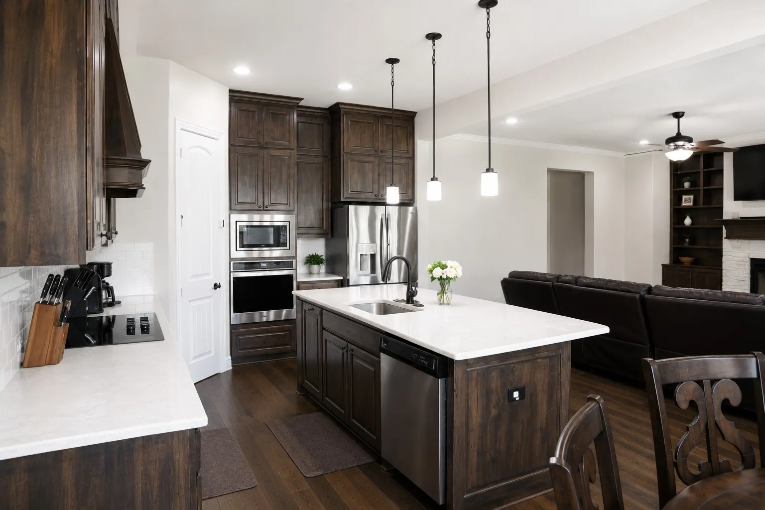 Spacious kitchen featuring dark wood-finish cabinetry, white countertops, and stainless steel appliances