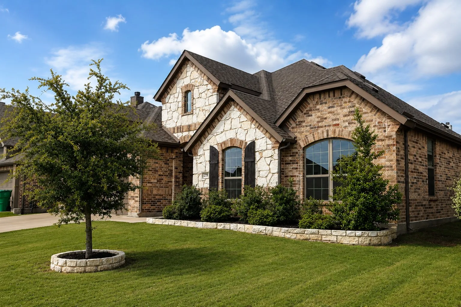 Exterior featuring brick and stone facade, arched windows, dark shutters, and a dark shingle roof