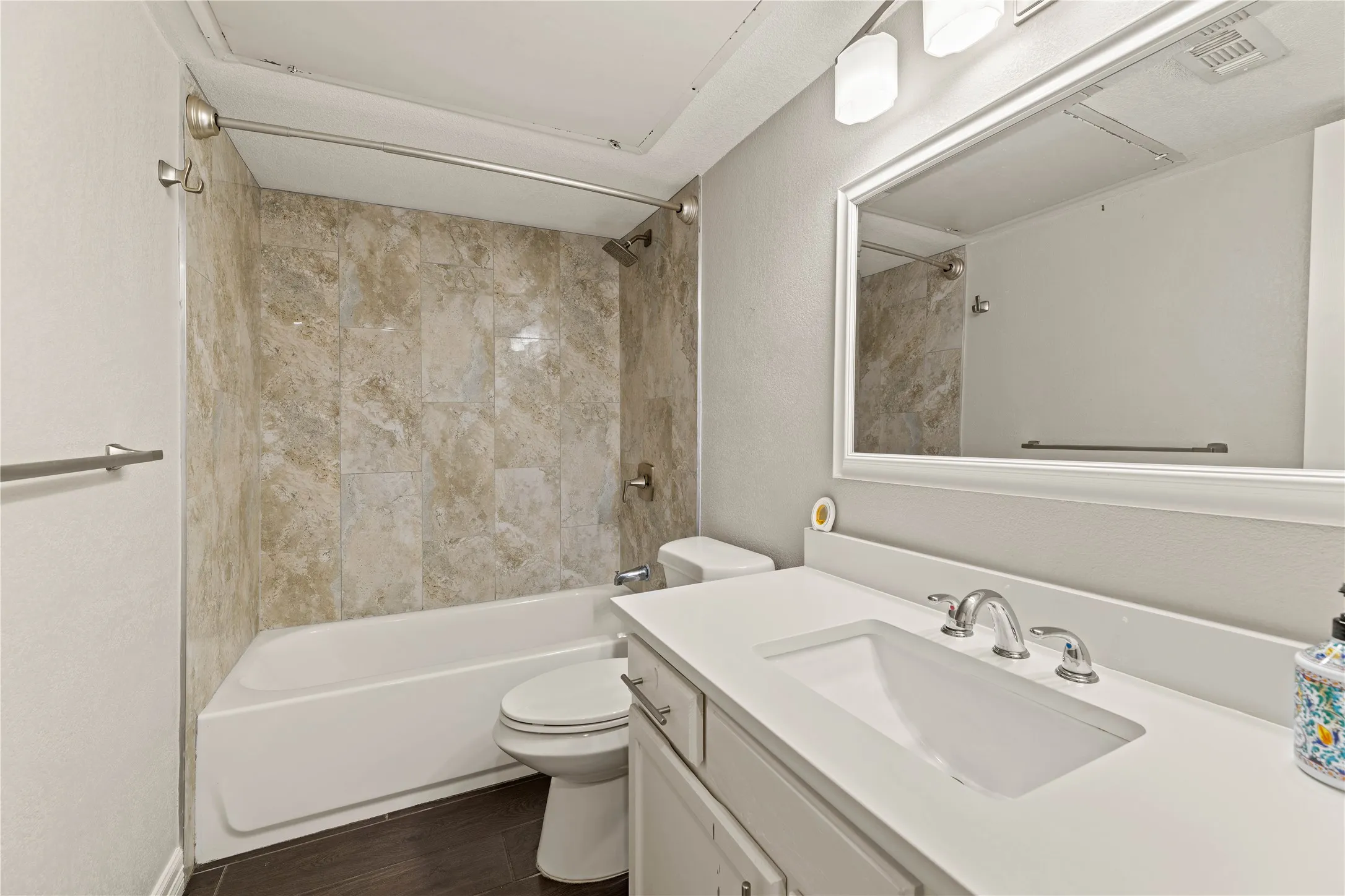 Bathroom featuring a white vanity with an integrated sink, chrome faucet, and a framed mirror