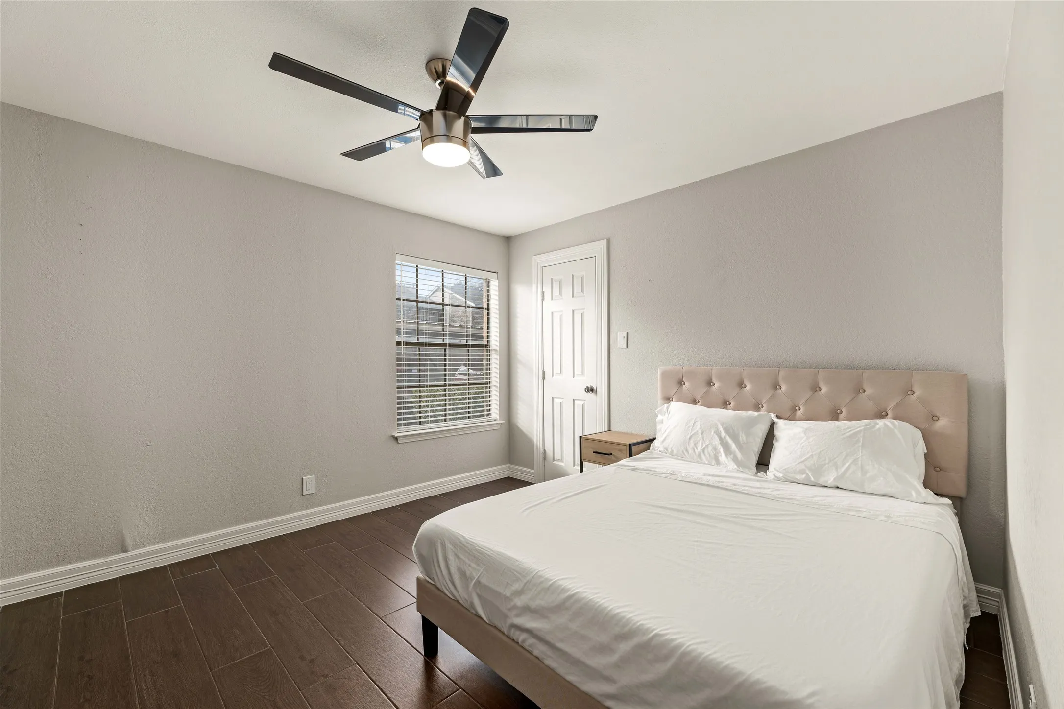 Bedroom featuring wood-finish flooring, a window with horizontal blinds, and a ceiling fan with integrated lighting