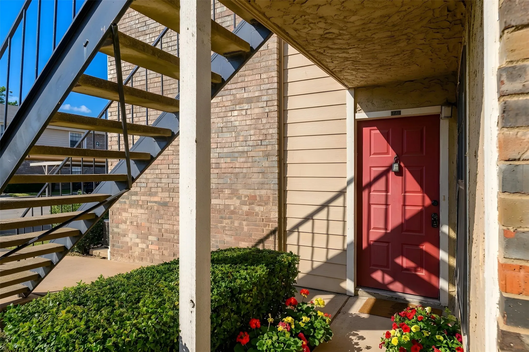 Entryway featuring a paneled red door, brick façade, and horizontal siding
