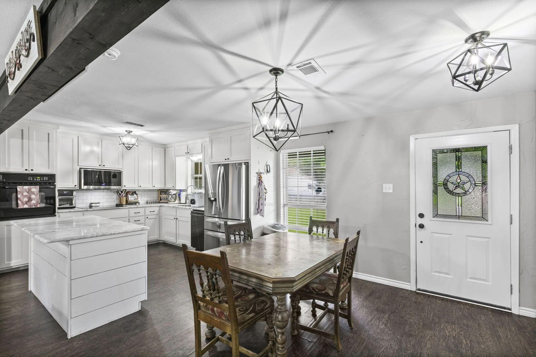 Kitchen featuring white cabinetry, stainless steel appliances, a center island with a white countertop, and dark wood-finish flooring