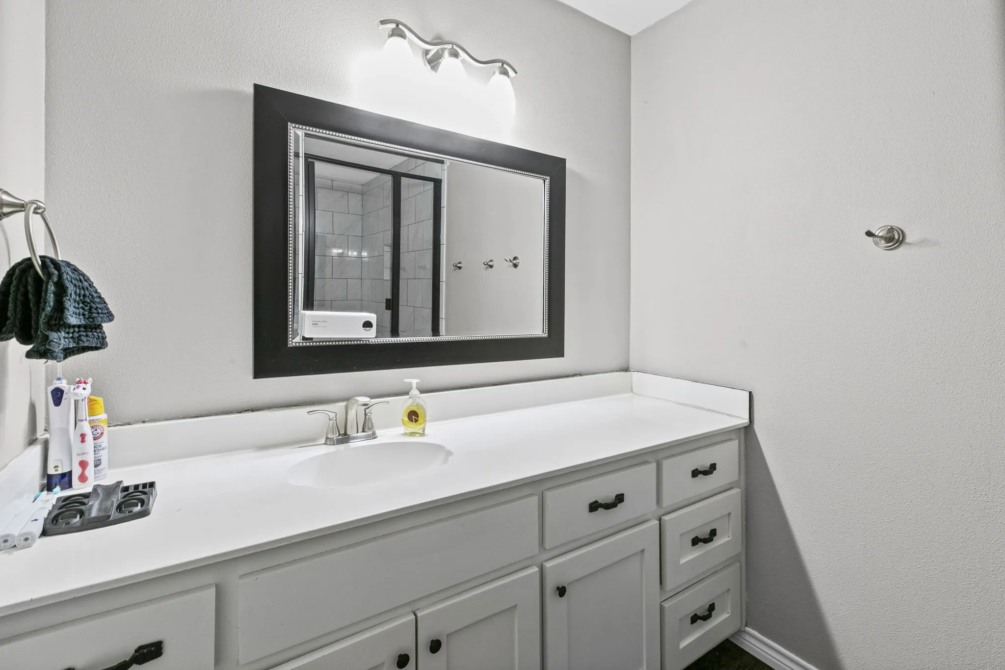 Bathroom vanity featuring a white countertop with an integrated sink, brushed nickel faucet, and a large framed mirror