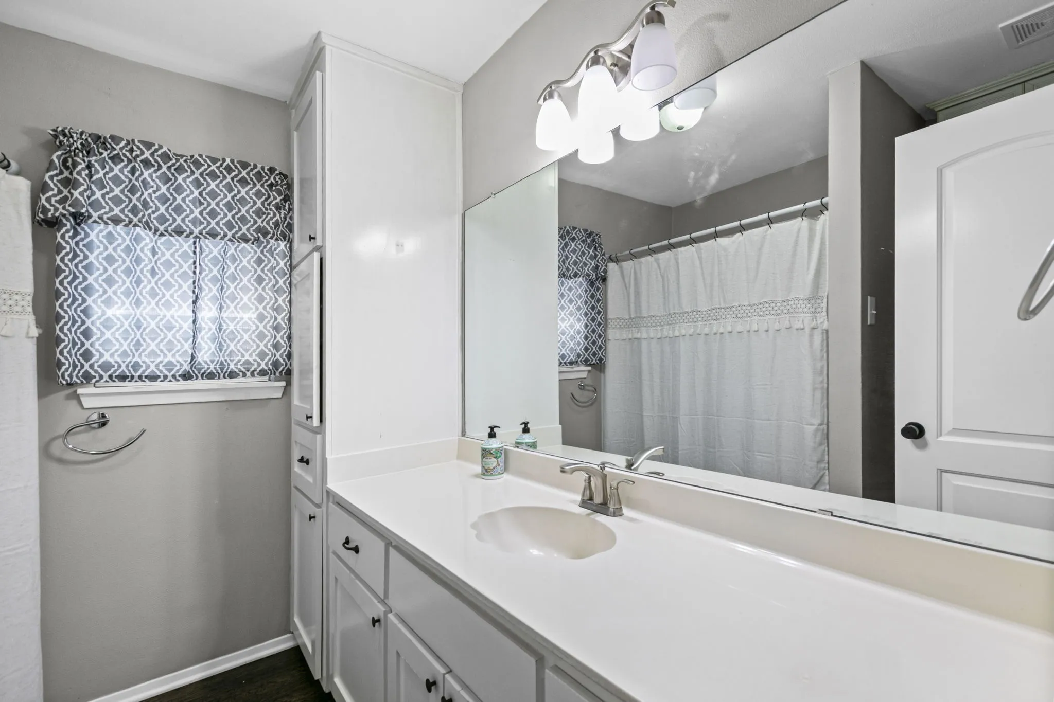 Bathroom featuring a single vanity with an integrated sink, brushed nickel faucet, and a large wall-mounted mirror
