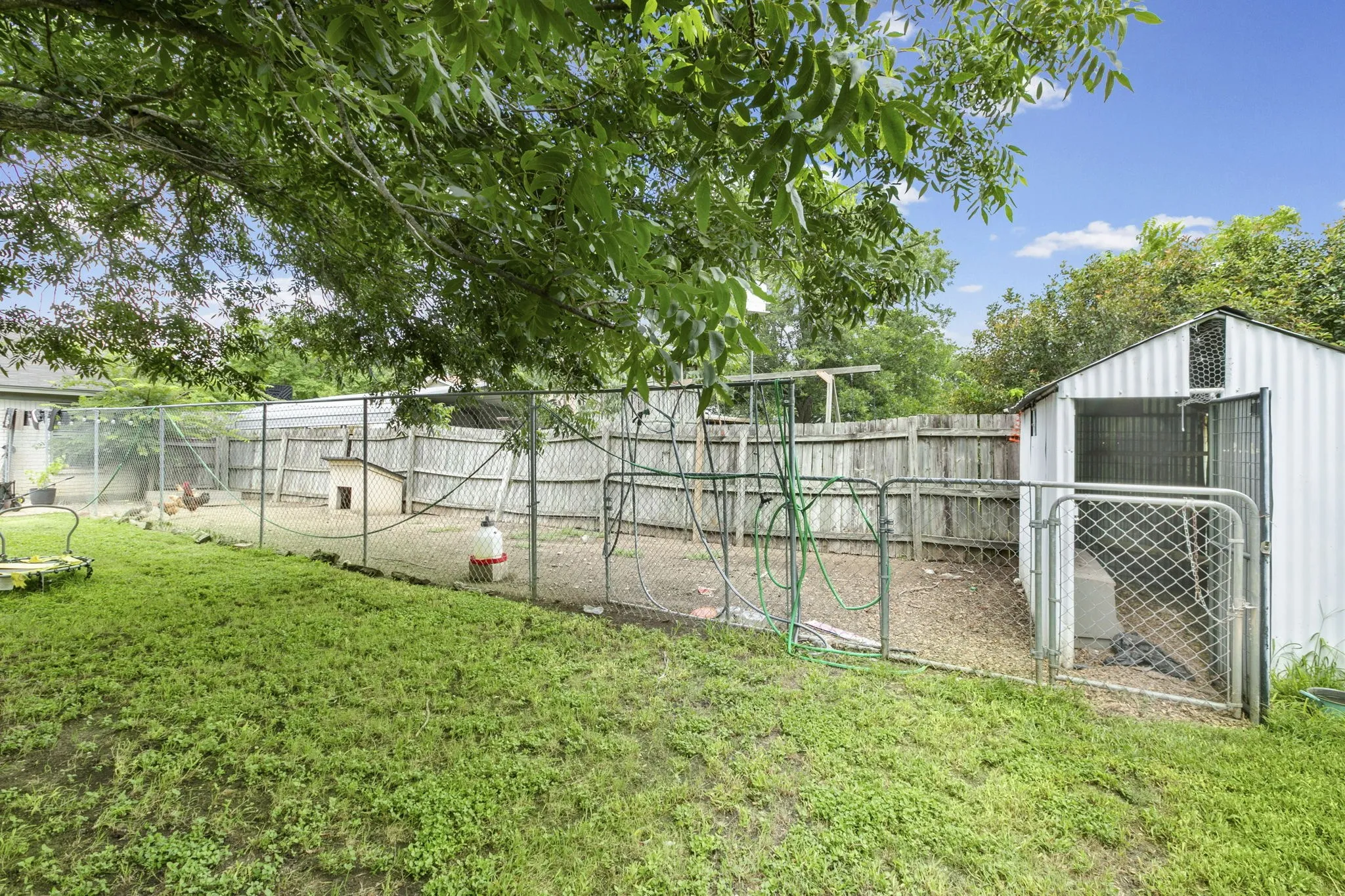 Fenced outdoor area featuring a metal utility shed, chain-link enclosure, and wood privacy fencing
