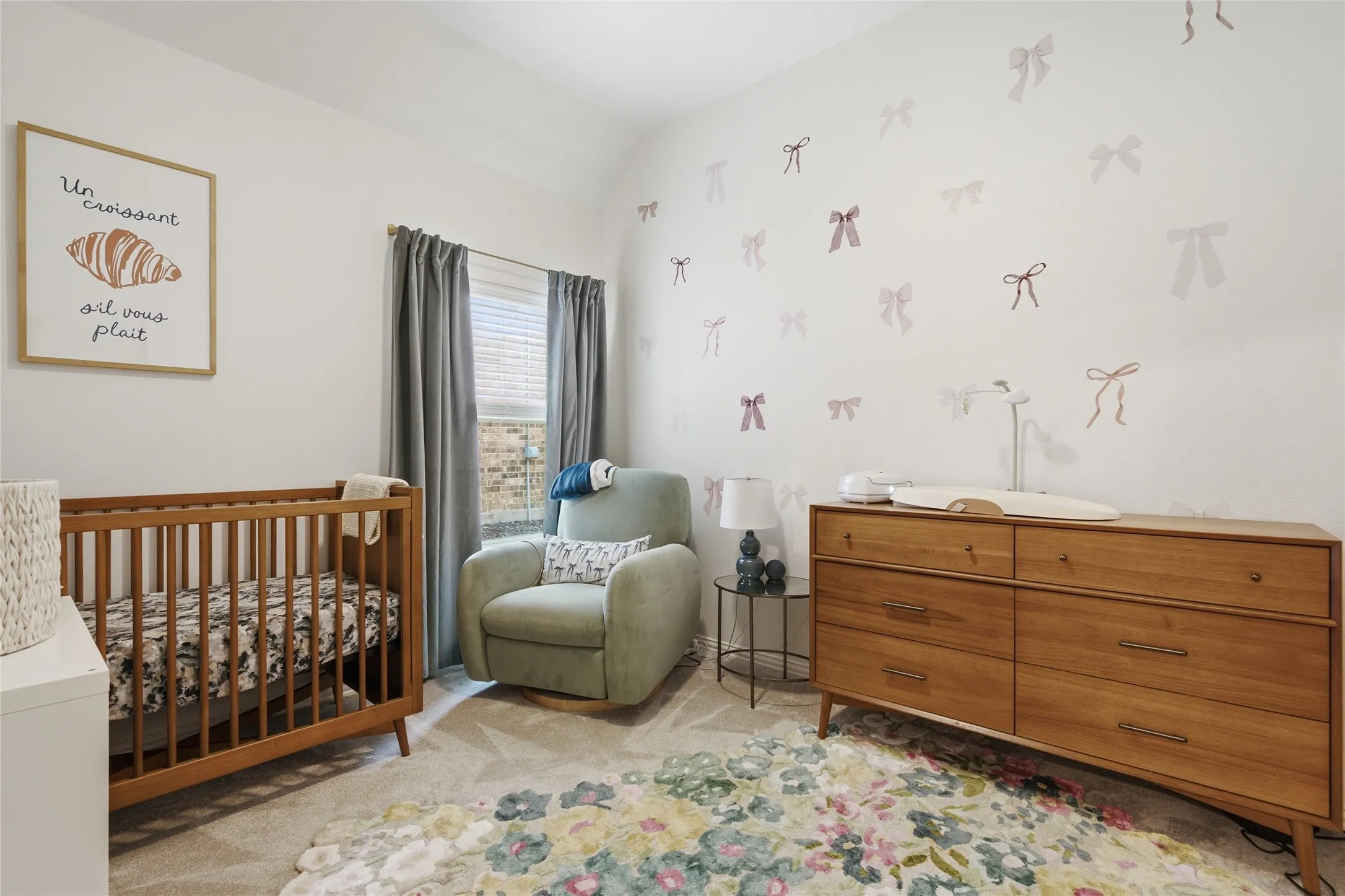Carpeted room featuring a window with blinds and drapes, and a wall adorned with bow accents