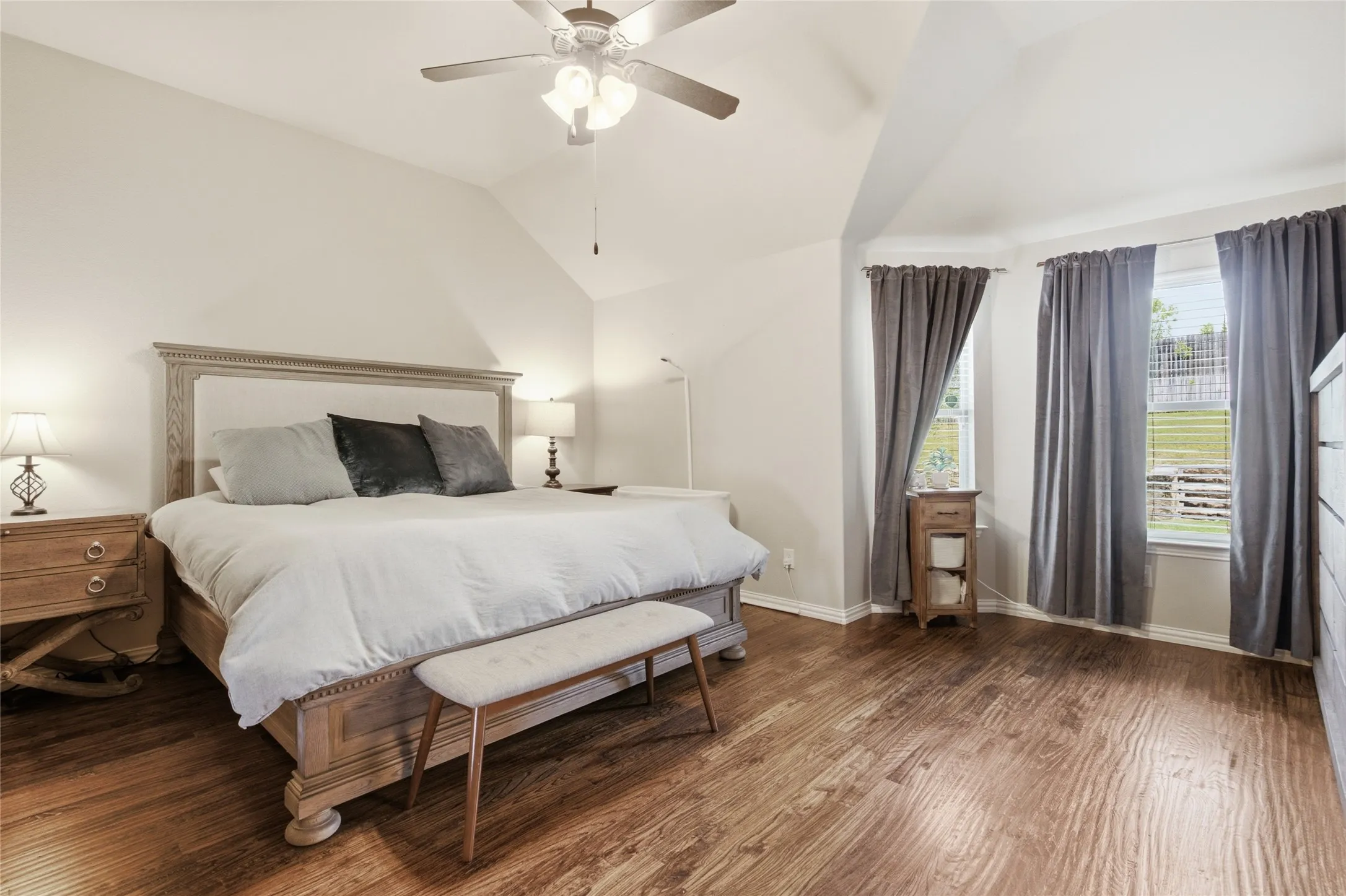 Bedroom featuring custom hardwood floors, vaulted ceilings, and a ceiling fan with integrated lighting