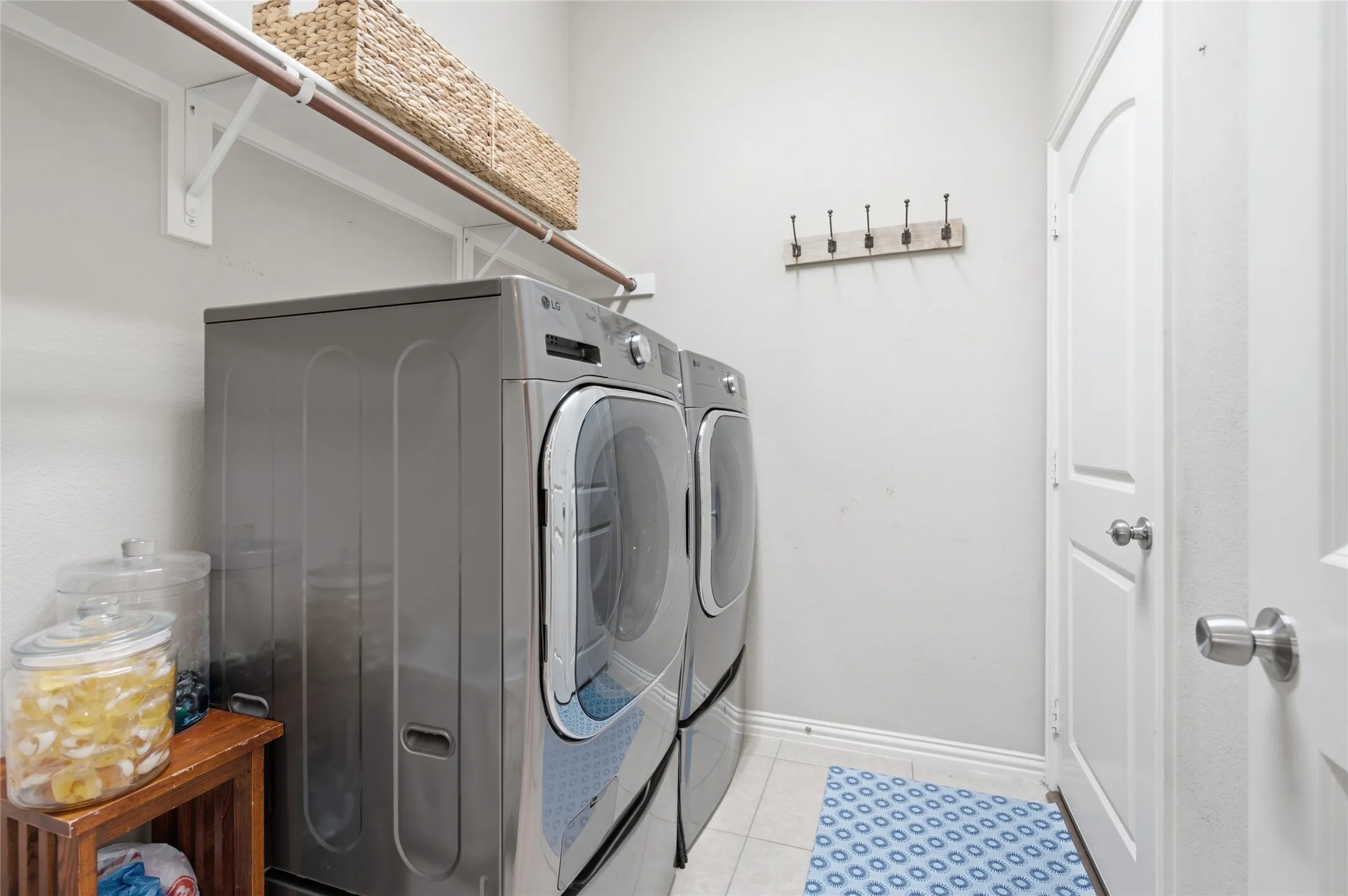 Dedicated laundry area featuring hanging space, shelving and room for a refrigerator.