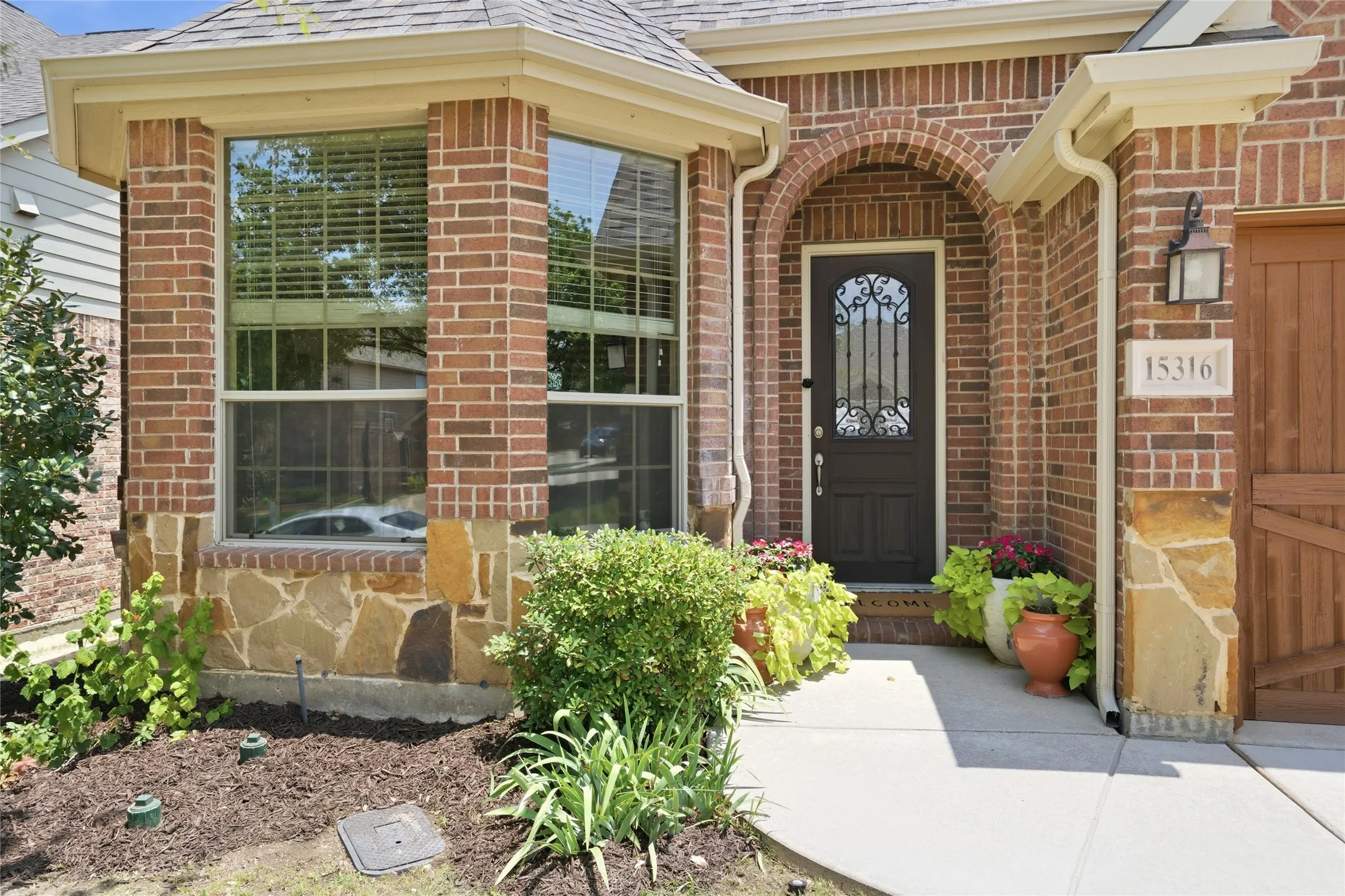 Brick exterior with stone wainscoting and a covered arched entryway
