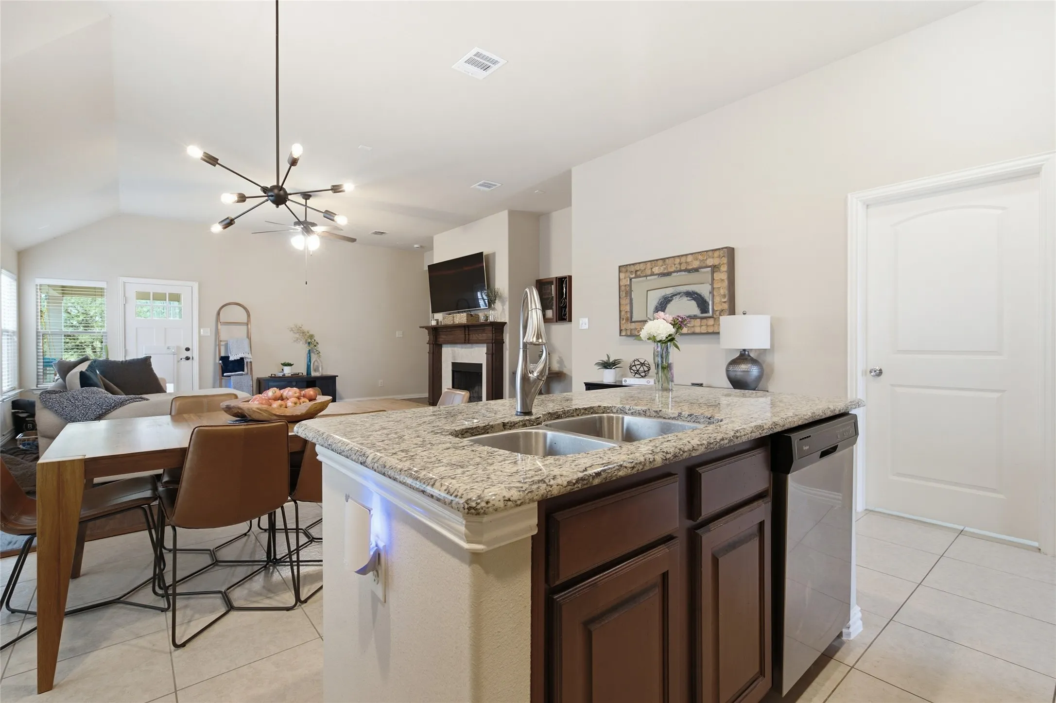 Kitchen island with a double basin sink, granite countertop, and dark wood cabinetry