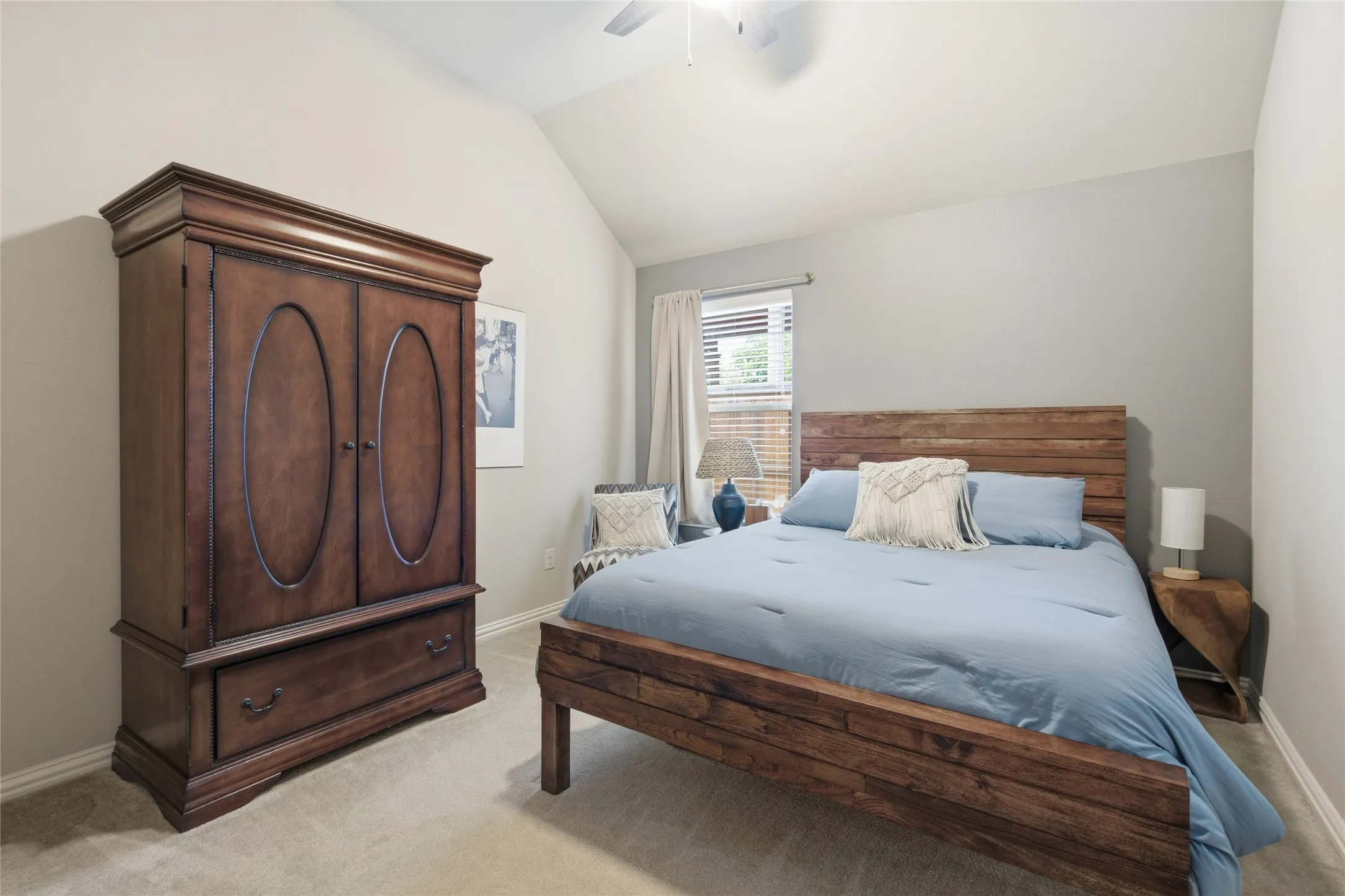 Vaulted ceiling bedroom featuring light gray painted walls and neutral carpet flooring