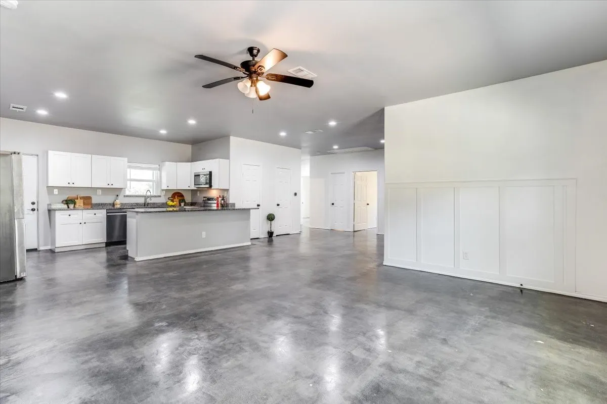 Open-concept living space featuring polished concrete flooring, recessed lighting, and a ceiling fan