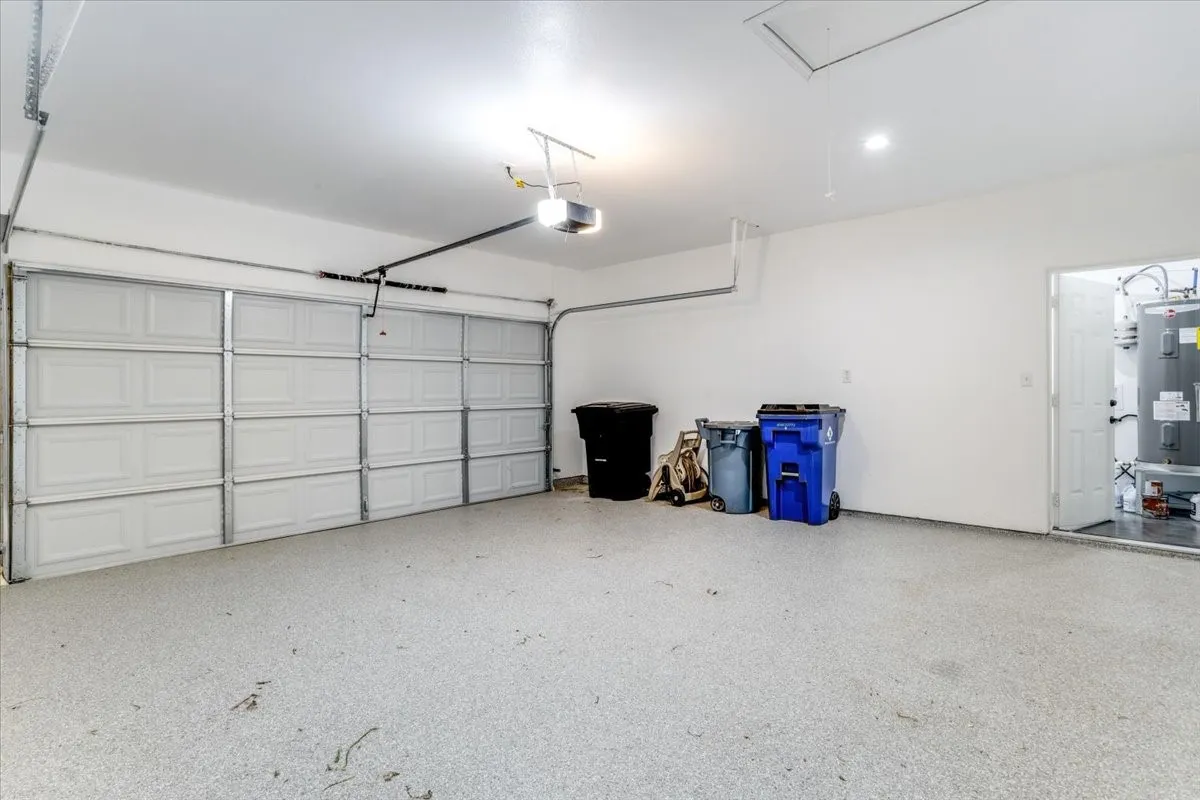 Spacious garage featuring a two-car overhead door, light-colored speckled flooring, and white painted walls