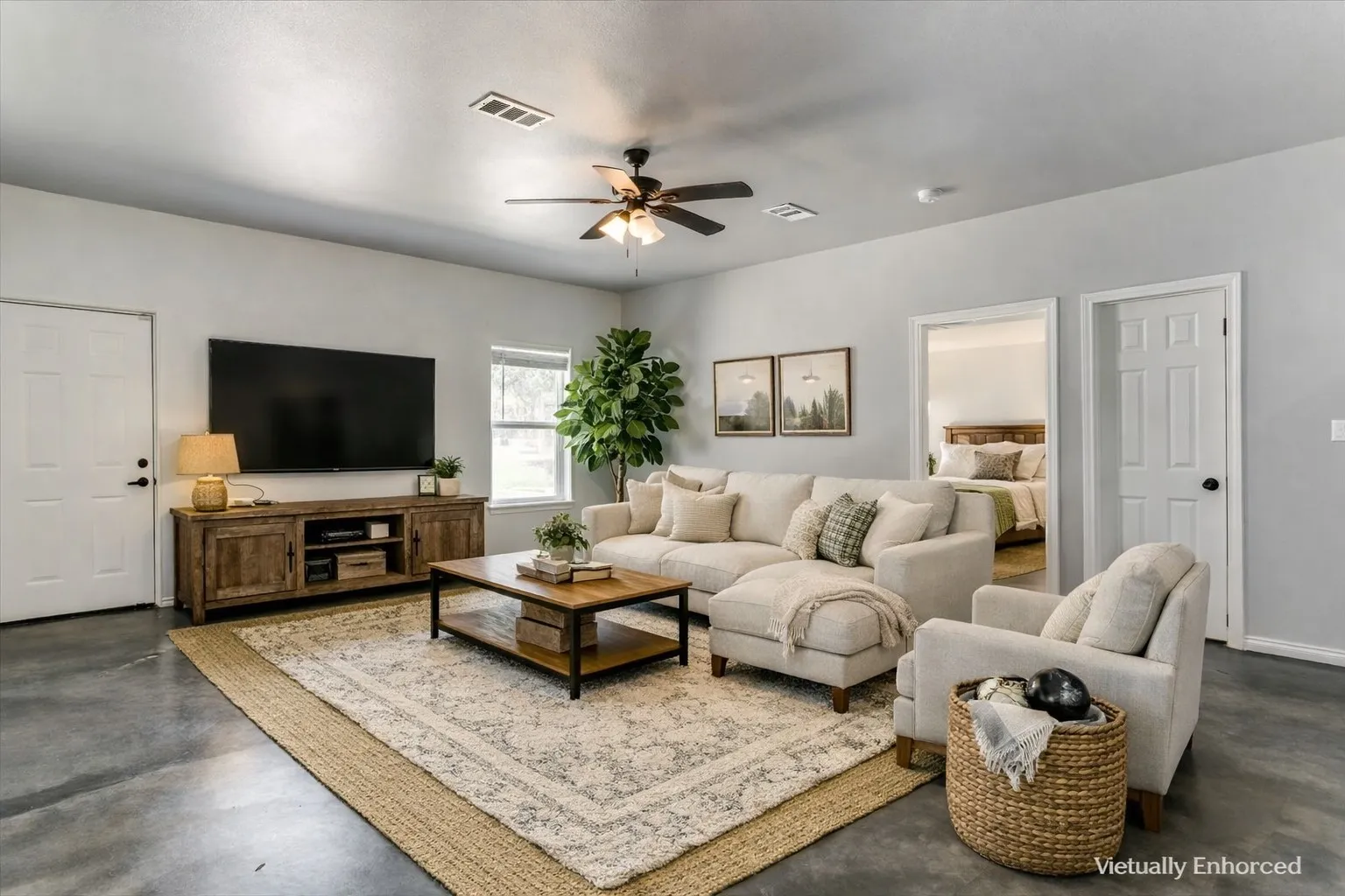 Spacious living area featuring light gray walls, a ceiling fan, and concrete flooring
