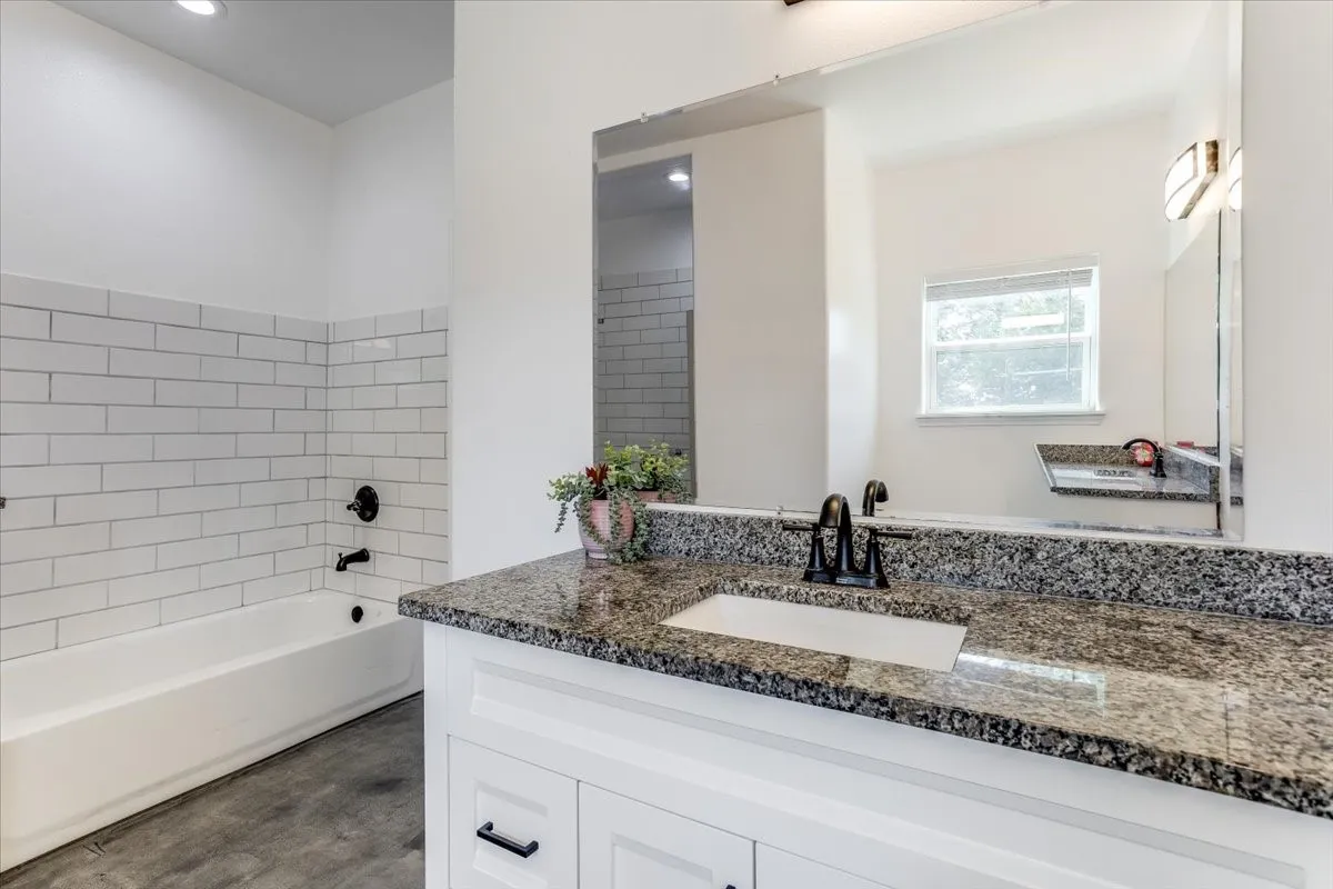 Bathroom vanity featuring a speckled countertop, undermount sink, and black faucet