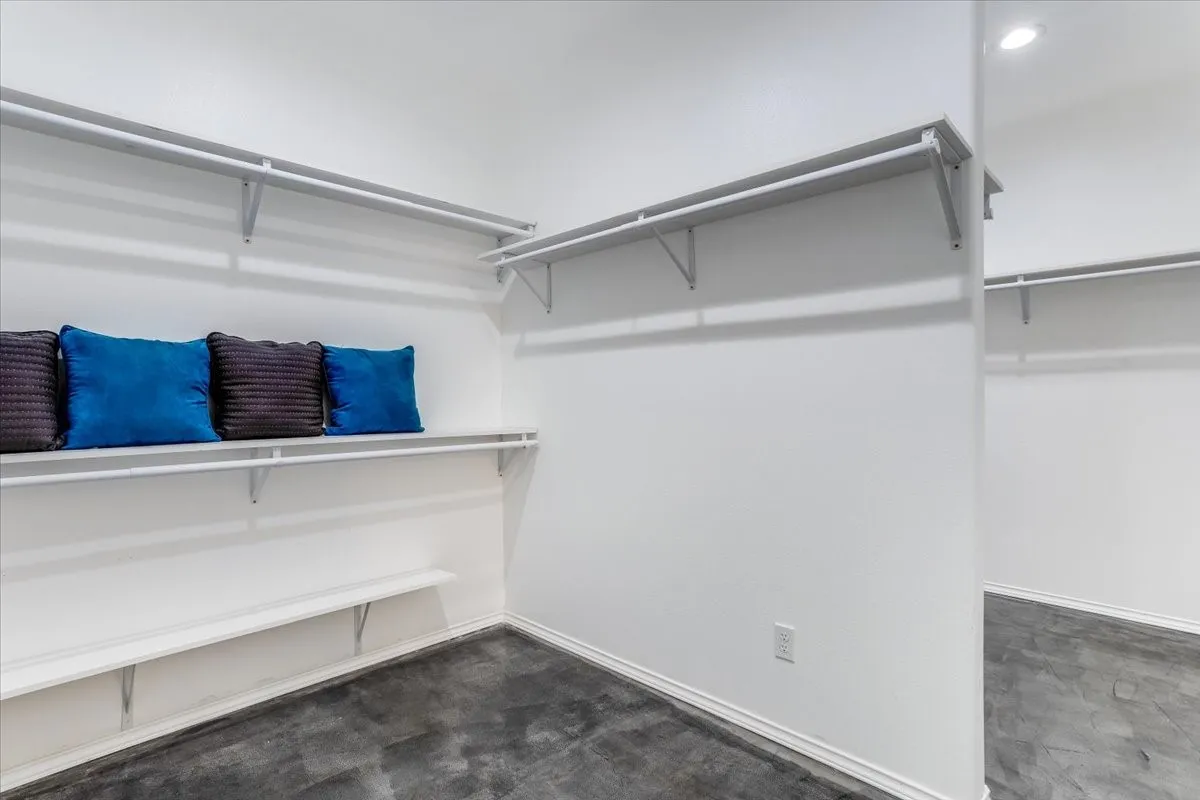 Spacious closet with white walls and dark grey flooring