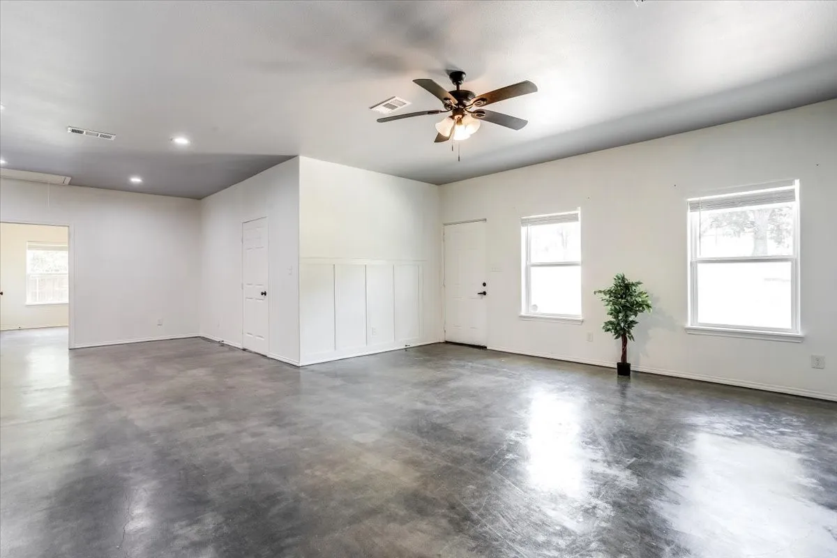 Spacious interior featuring a ceiling fan, recessed lighting, and polished concrete flooring