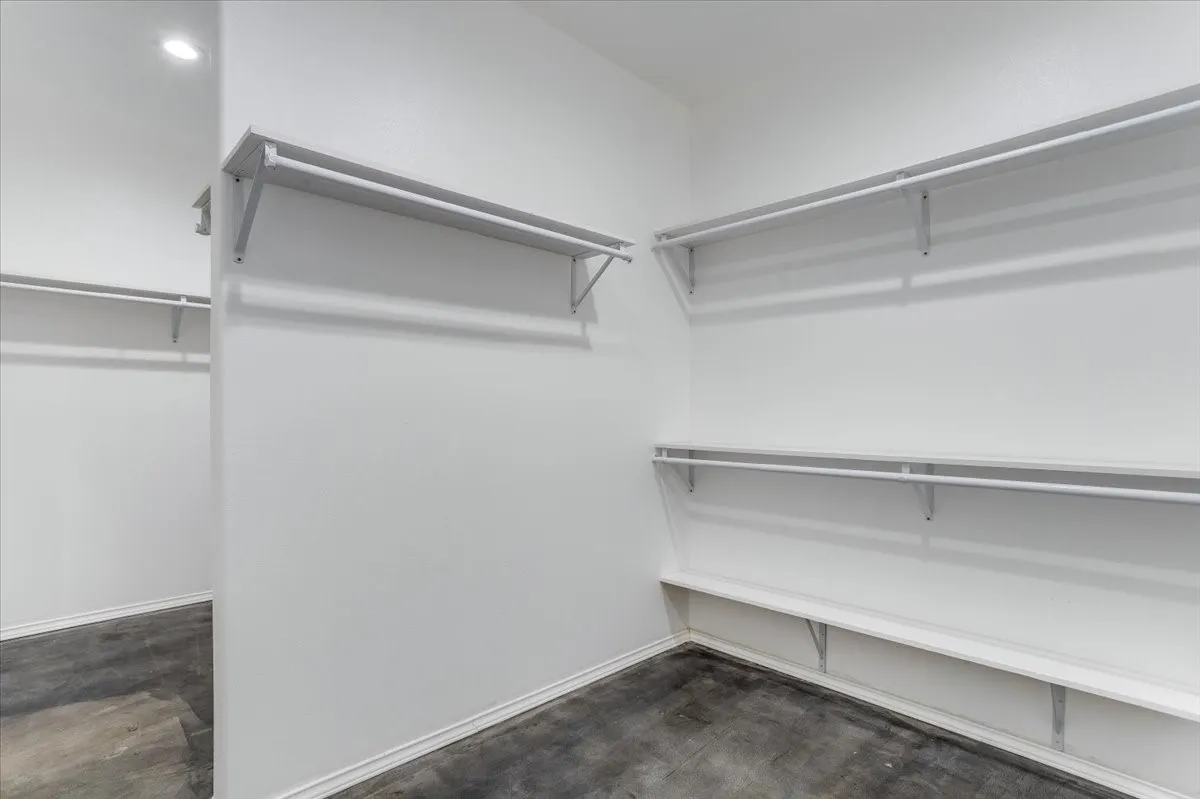 Spacious walk-in closet featuring multiple shelving units, clothing rods, and wood-finish flooring
