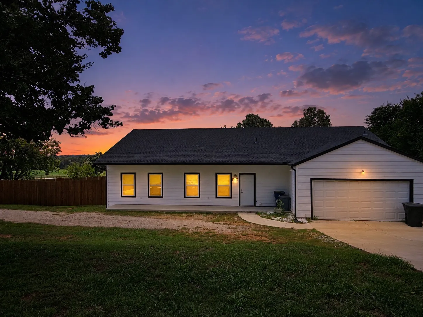 White siding exterior with a dark shingle roof and an attached garage