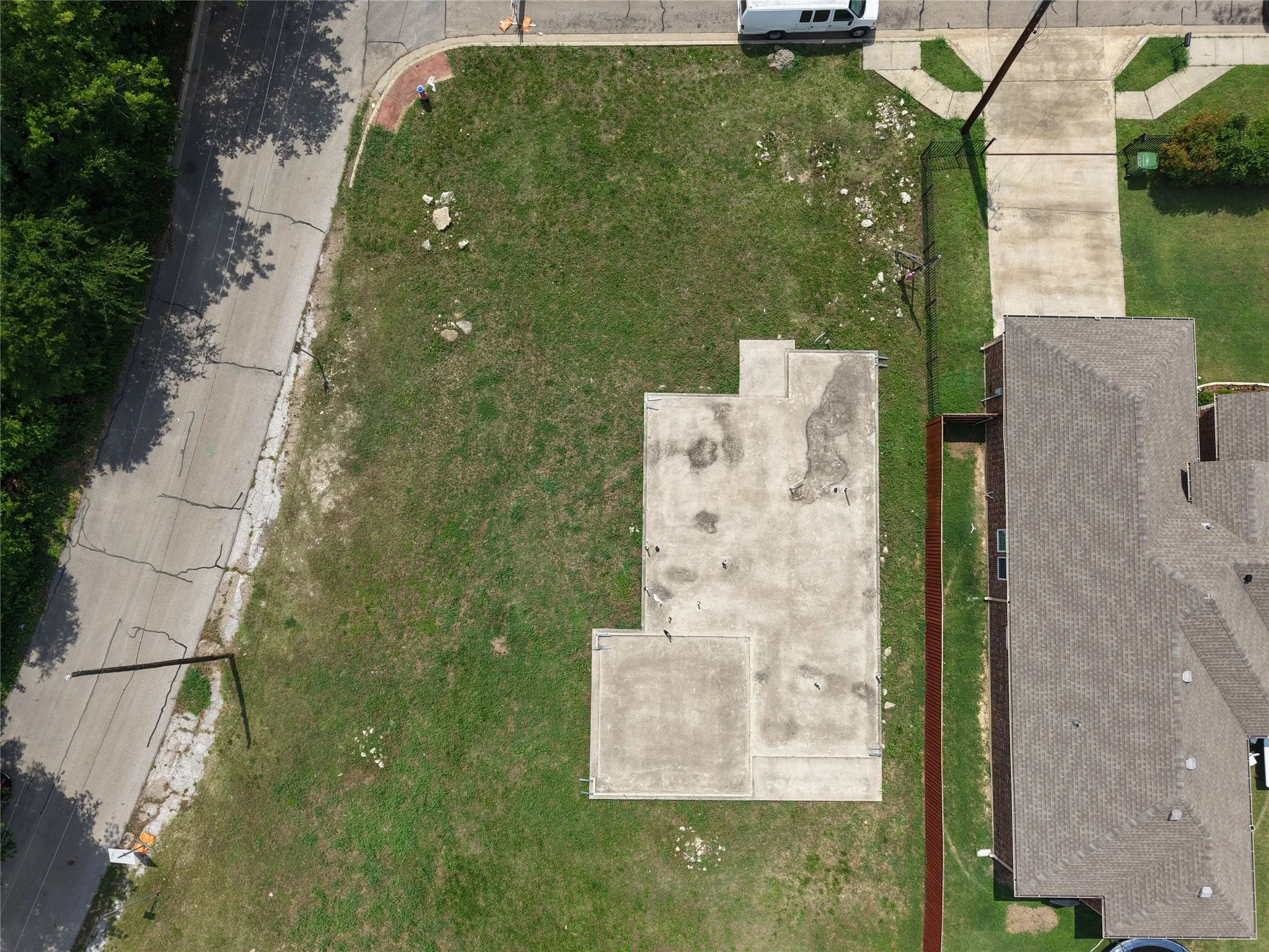 Concrete slab foundation on a grass lot, featuring a paved street frontage and a concrete sidewalk
