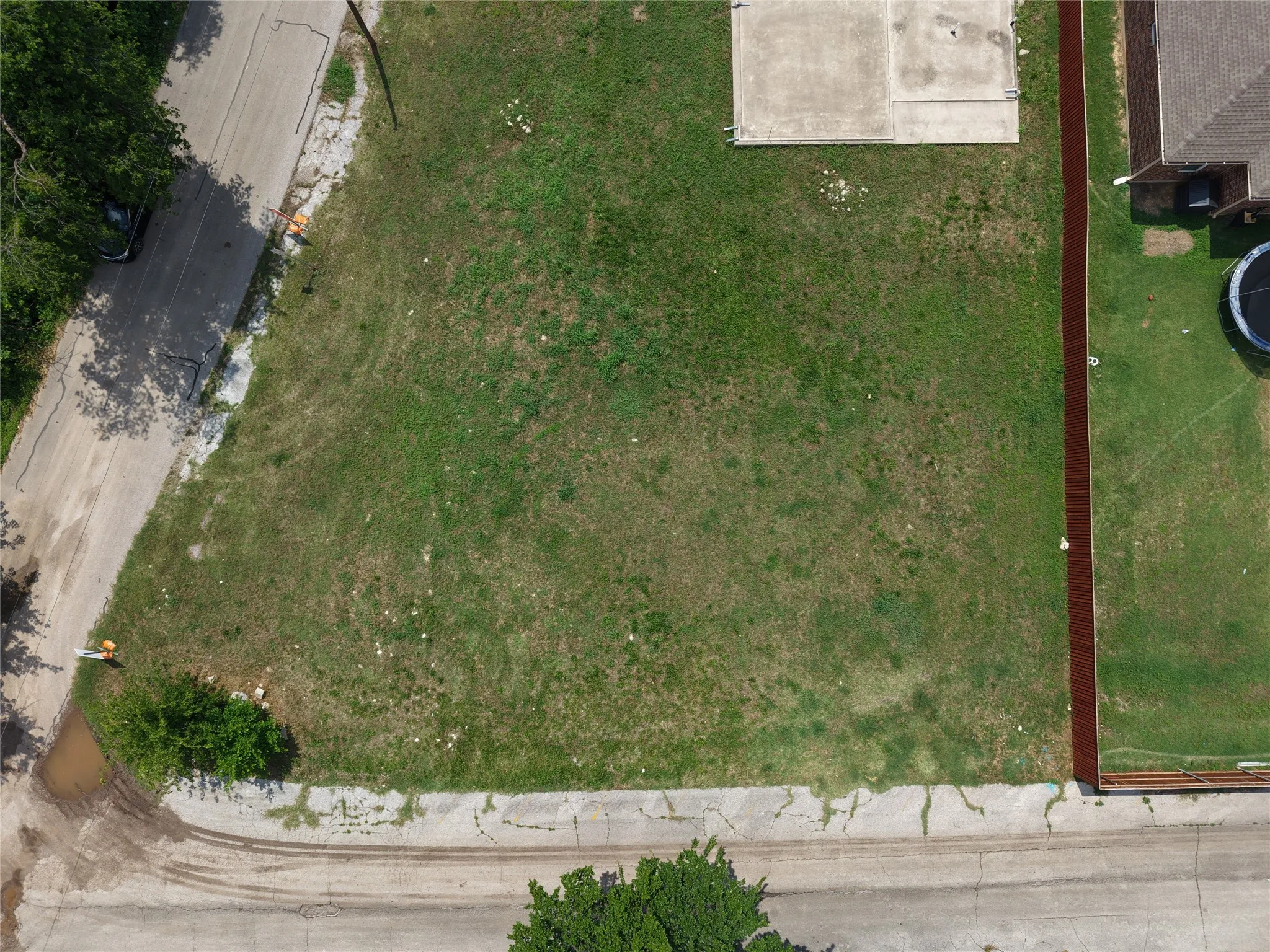 Cleared land parcel with partial fencing and concrete pad