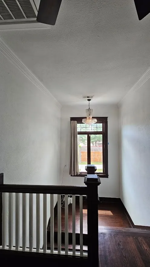 Dark wood-finish flooring with white walls and crown molding