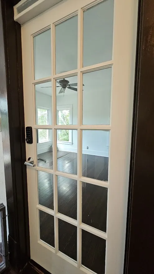 White French door with glass panels and dark wood-finish flooring