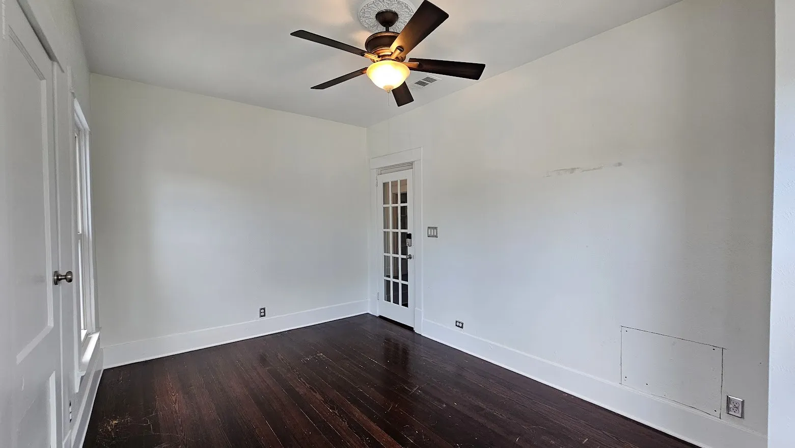Interior room featuring dark wood-finish flooring, white baseboards, and white painted walls