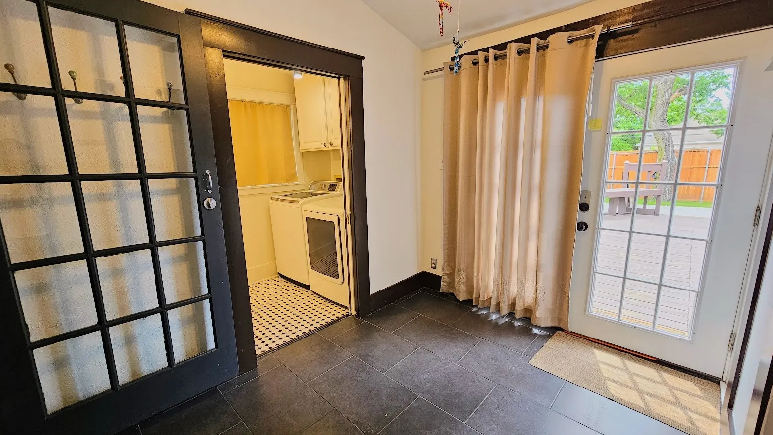 Mudroom area featuring dark rectangular floor tiles and a white paneled door with grid-patterned glass providing exterior access