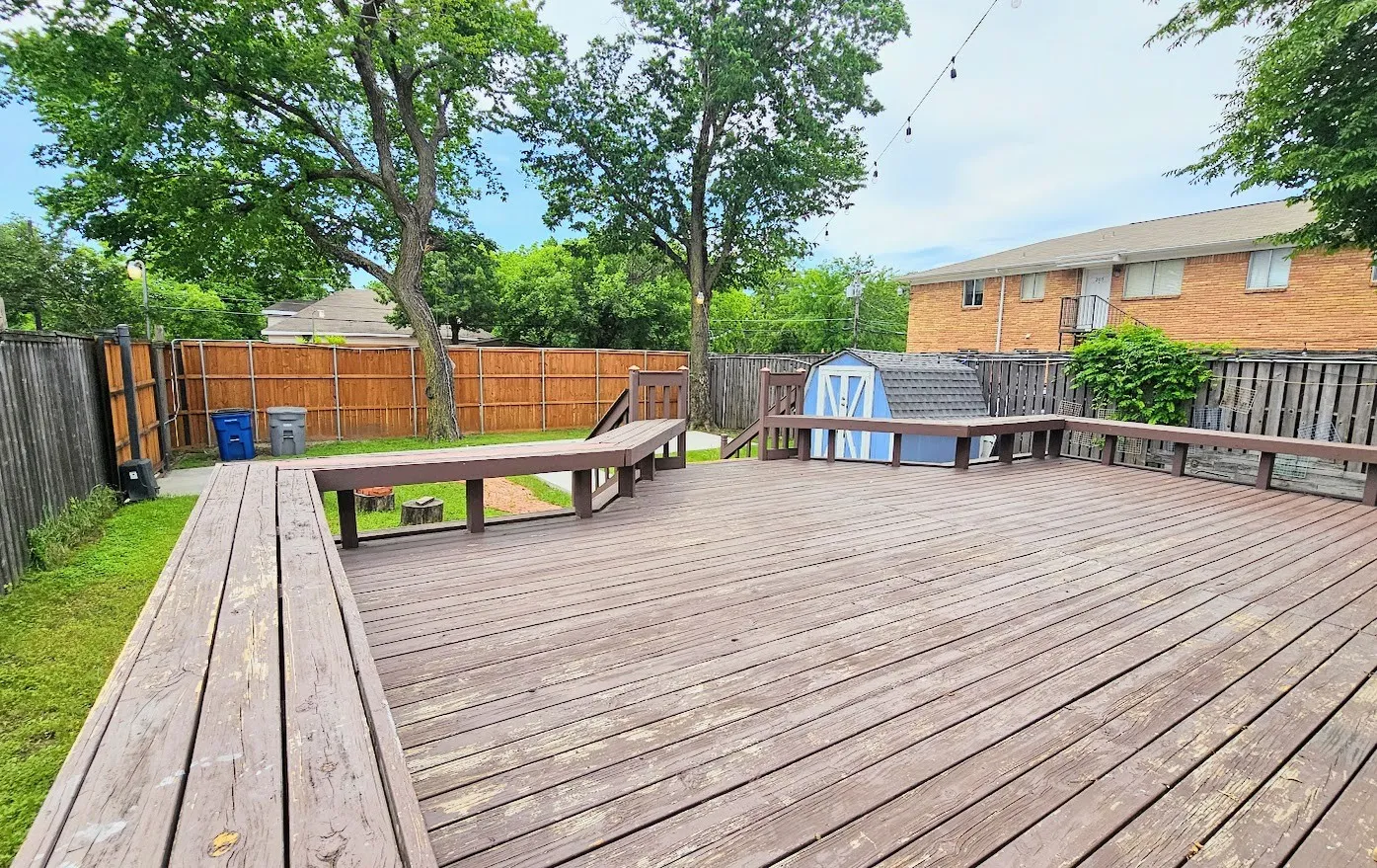 Expansive wood deck with built-in bench seating, a storage shed, and perimeter fencing