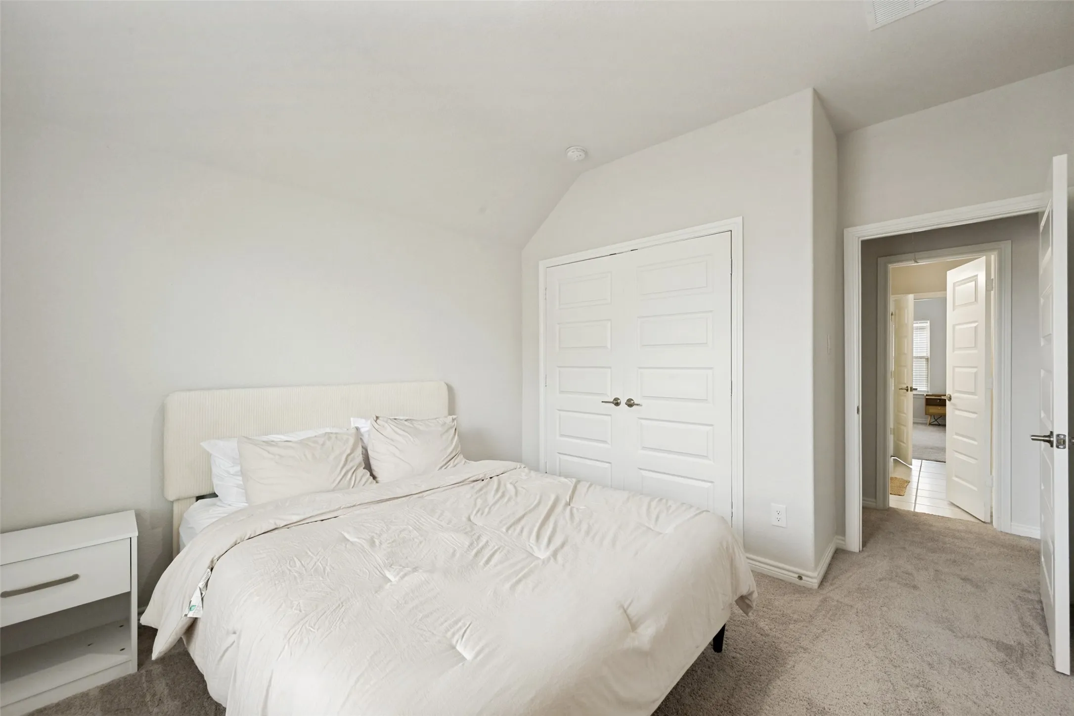 Bedroom featuring neutral carpeting, white walls, white paneled bifold closet doors, and recessed lighting