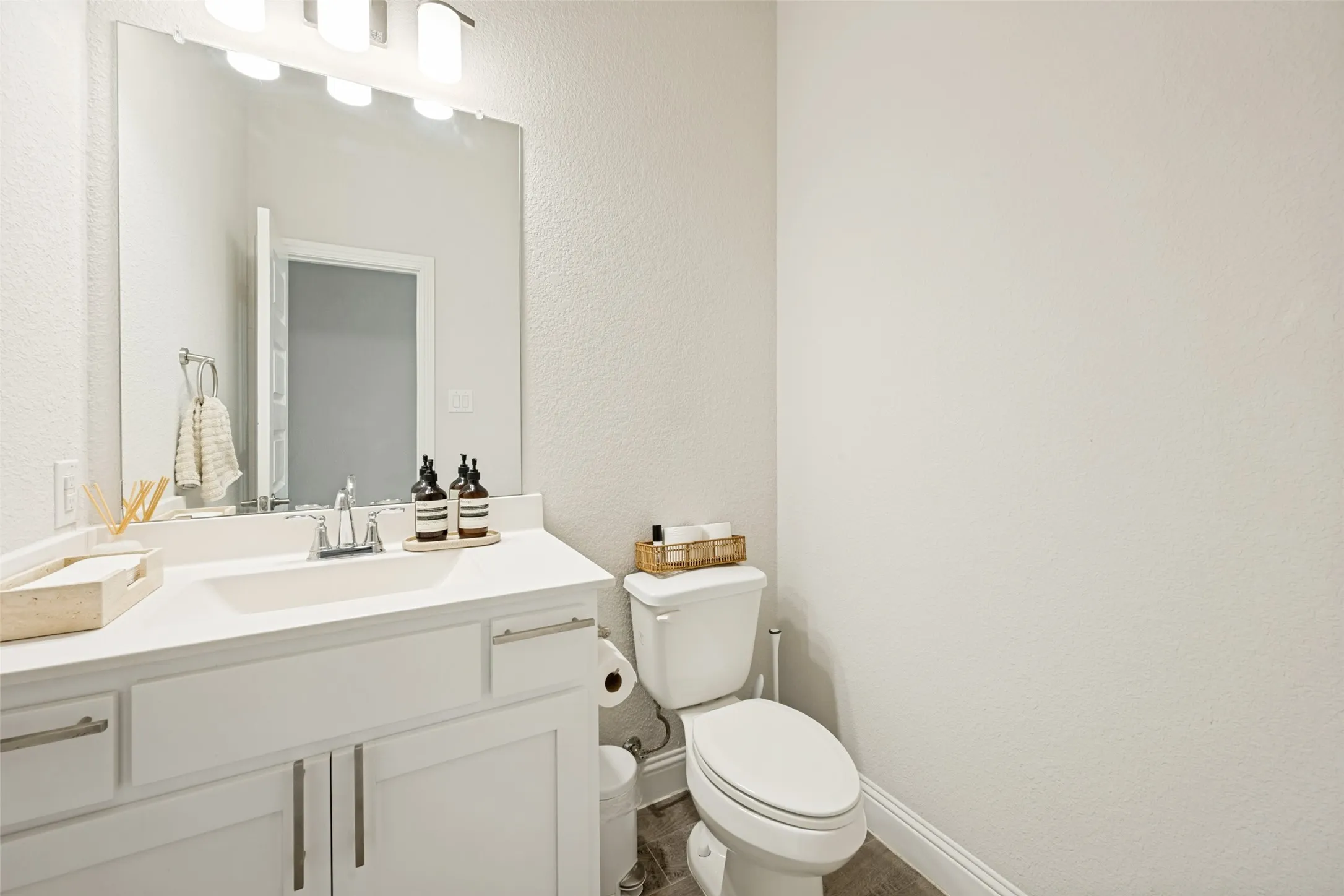 Bathroom featuring a white vanity with an integrated sink, chrome faucet, and a large mirror