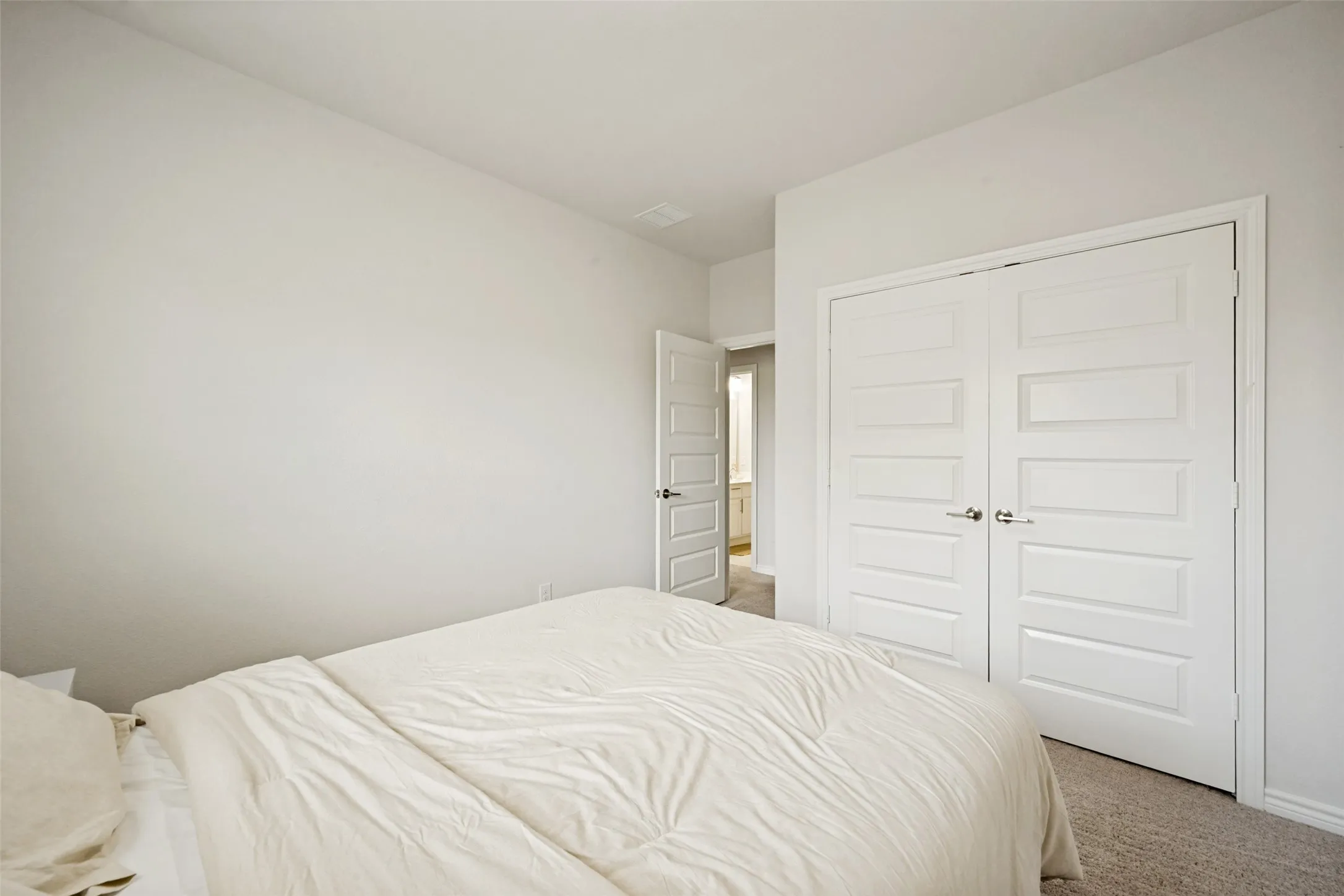 Carpeted room with white walls, white trim, and white five-panel bifold closet doors with satin nickel hardware
